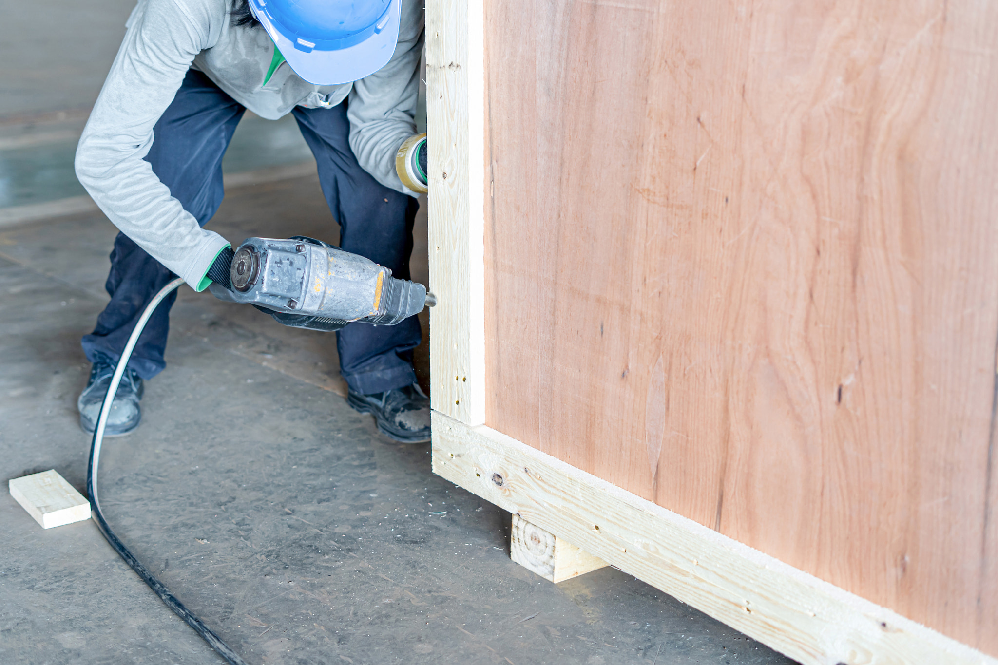 Closeup of a man using a pneumatic nail gun to finish the trim wooden box in packing work for storag