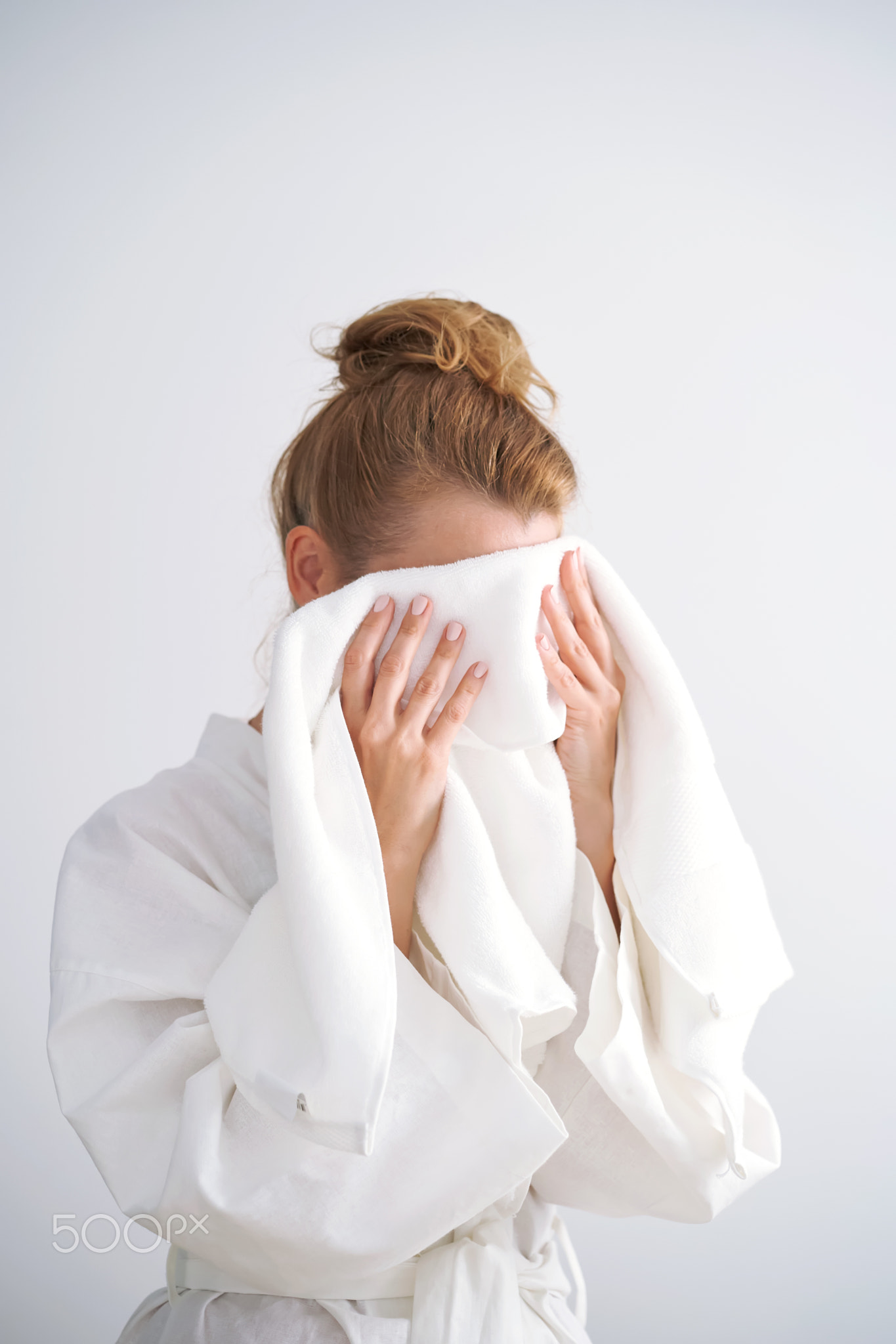 The girl wipes her face with a terry towel.