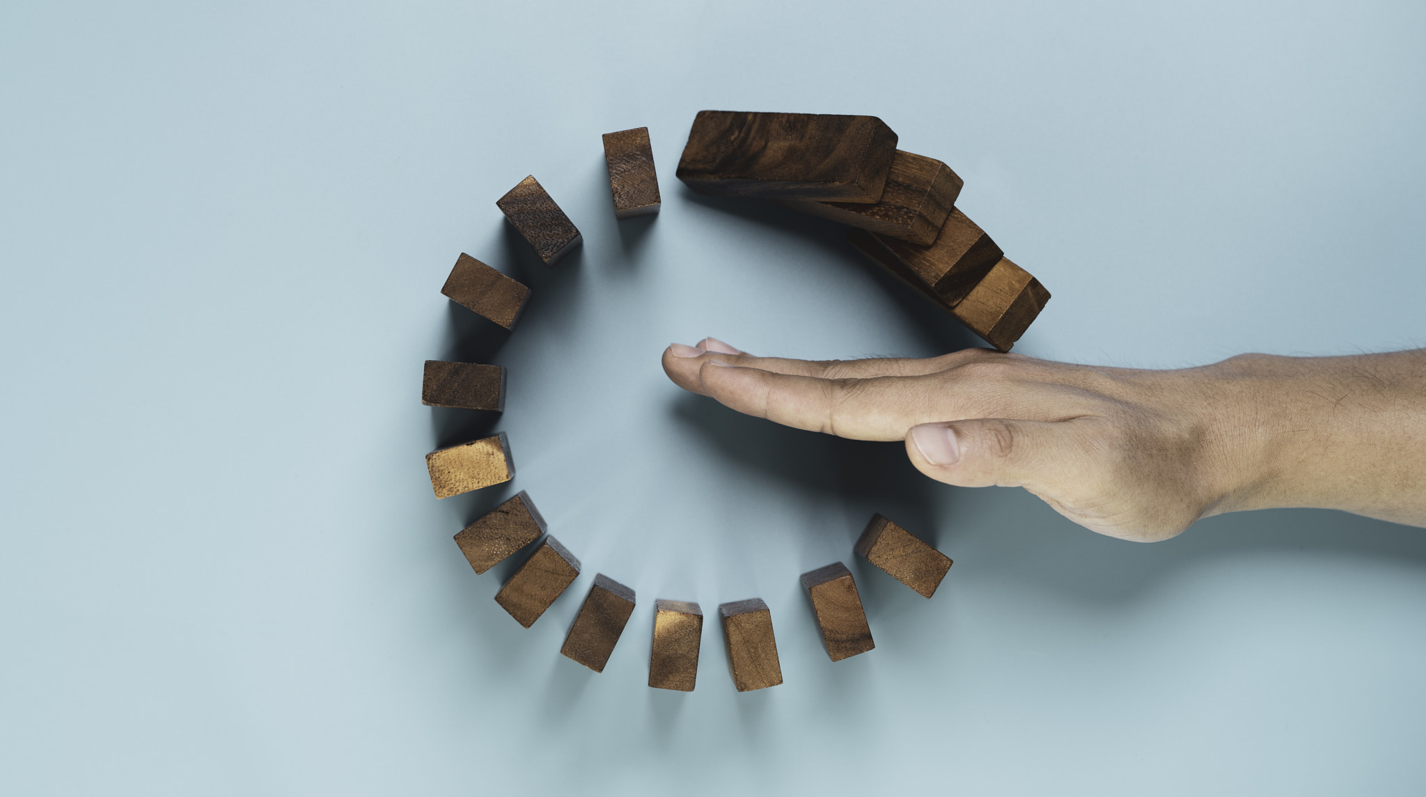 Top view and flat lay design of Businessman use gesture to stop wooden domino circle falling for ins