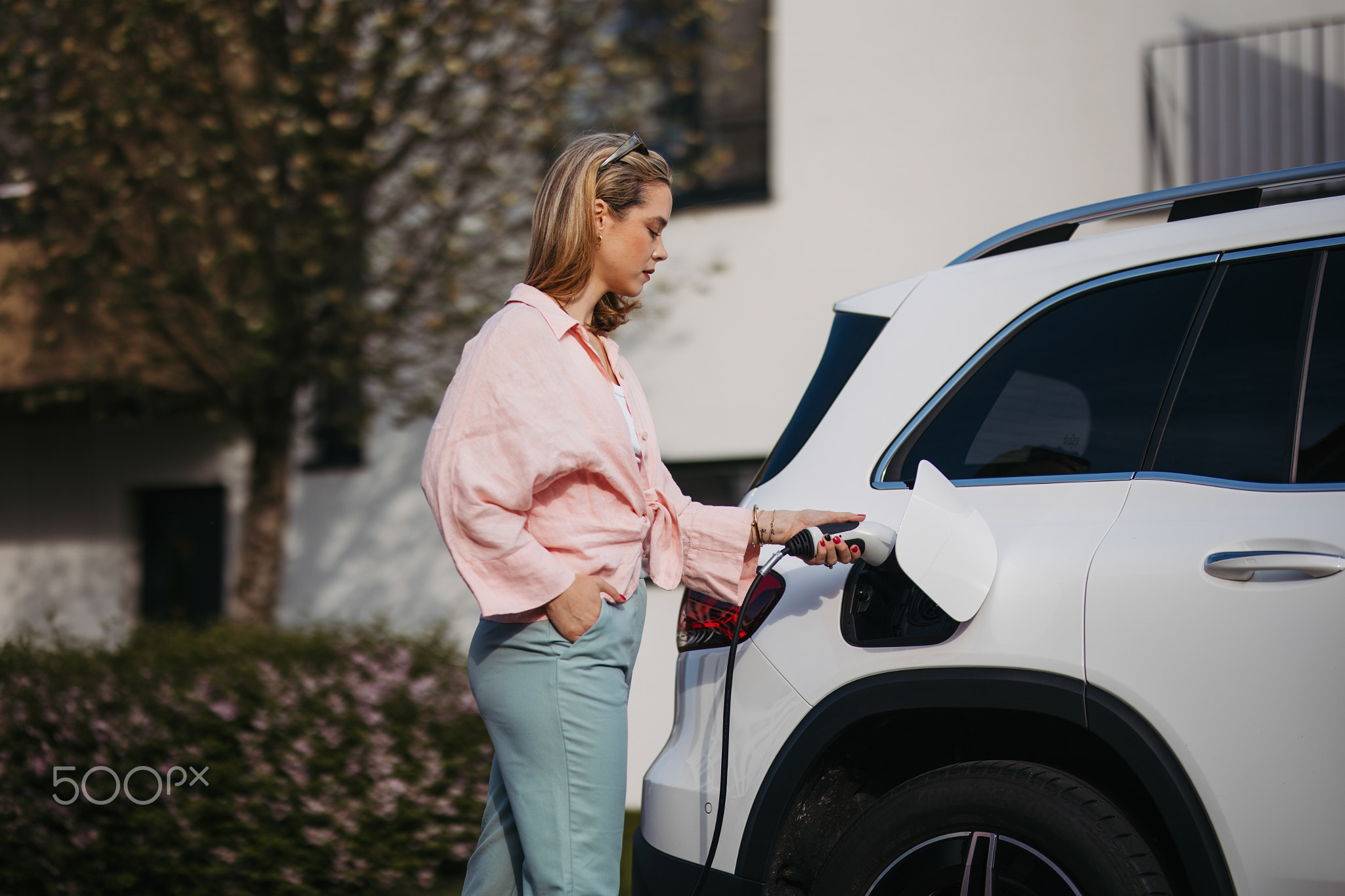 Woman charging her electric car, sustainable and economic transportation concept.