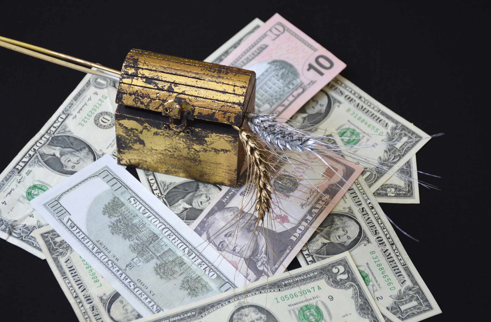 chest with a ripe ear of wheat against the background of dollars