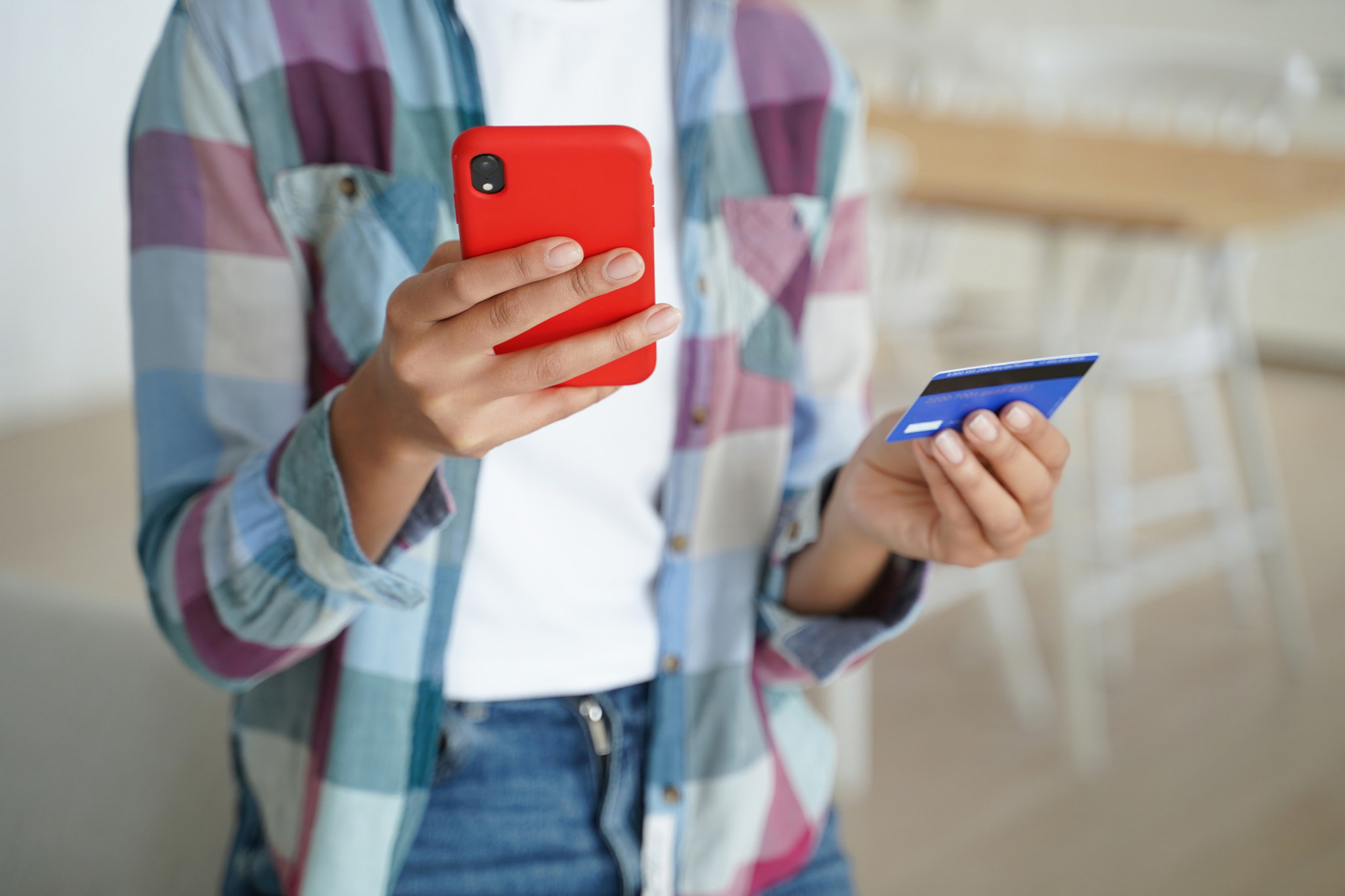 Secure online shopping: hands hold credit card, smartphone. Safe payments indoors.