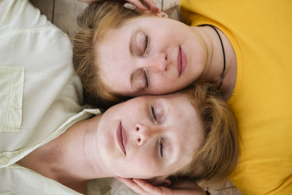 Two red-haired sisters lie cheek to cheek with their eyes closed. Similar women  by Evgeniia Freeman on 500px.com