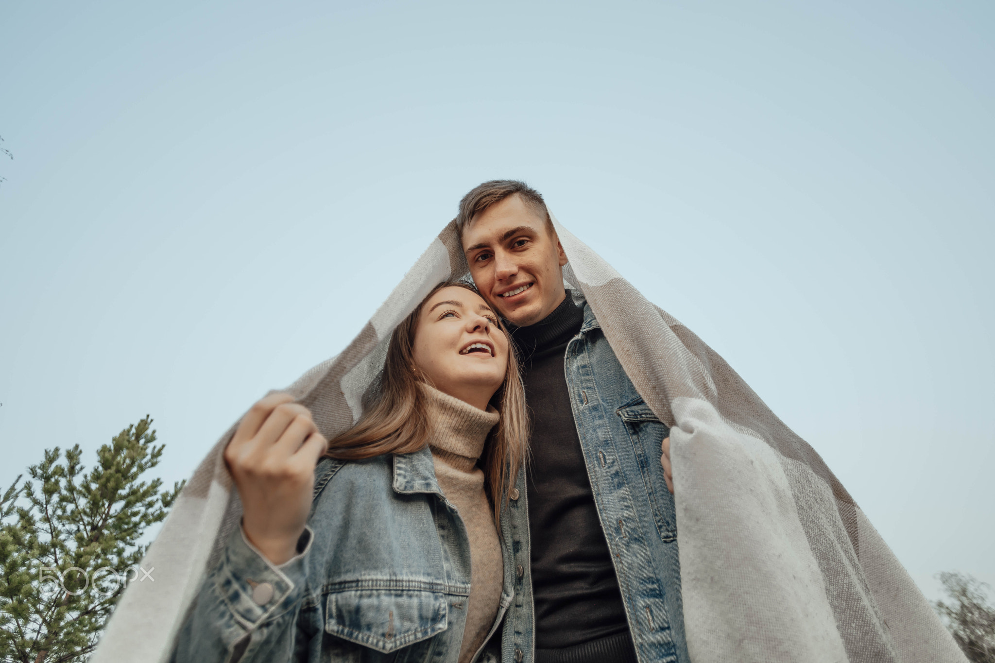 Young Couple UnderHome-Shaped Blanket: A Unique Concept for Mortgage
