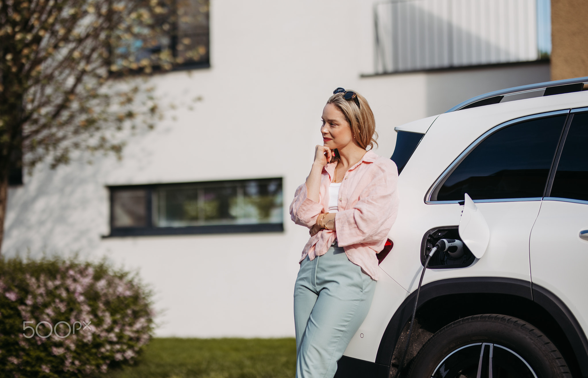 Young woman charging her electric car in home, sustainable and economic transportation concept.