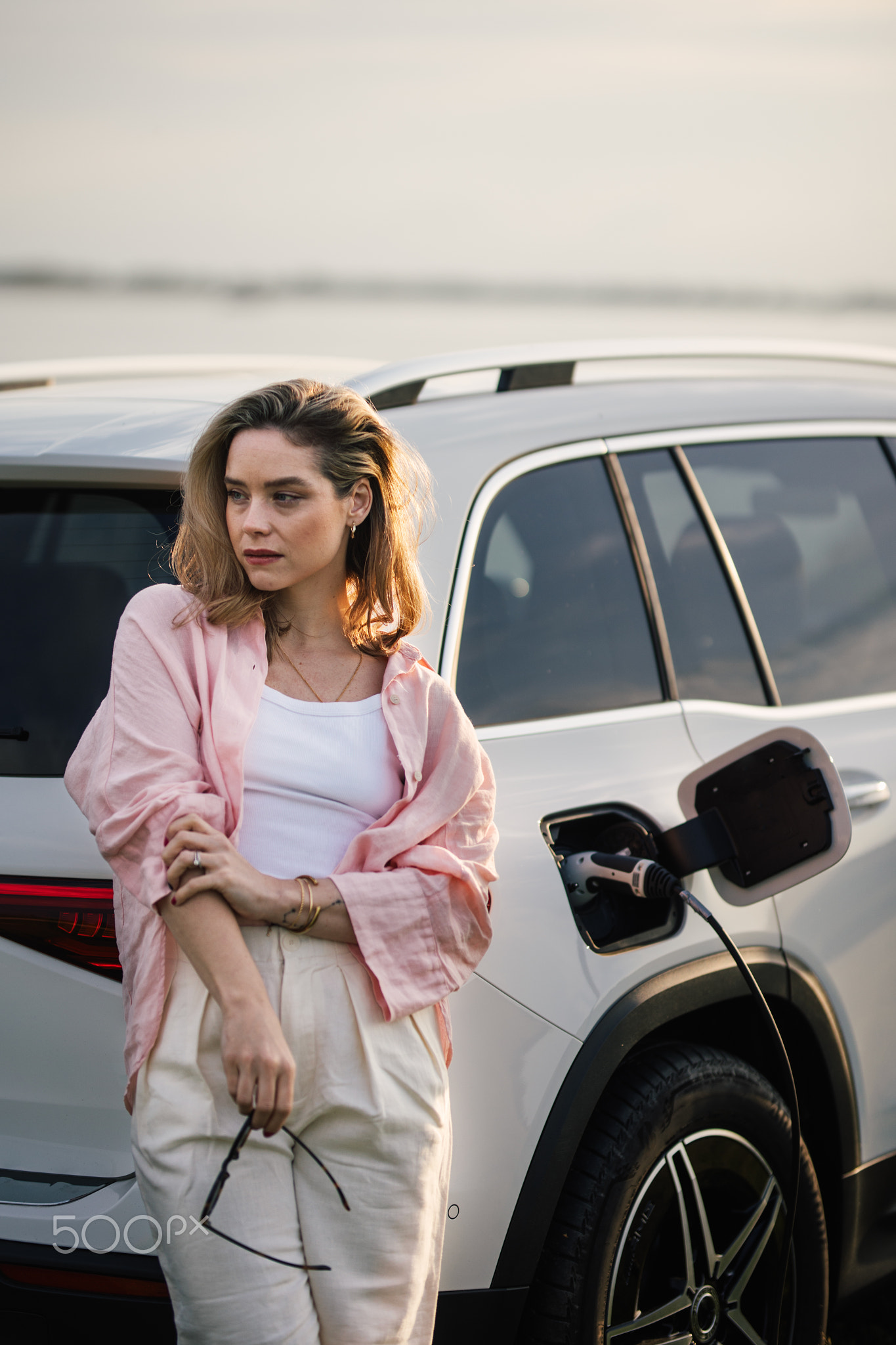 Woman waiting while charging her electric car, sustainable and economic transportation concept.