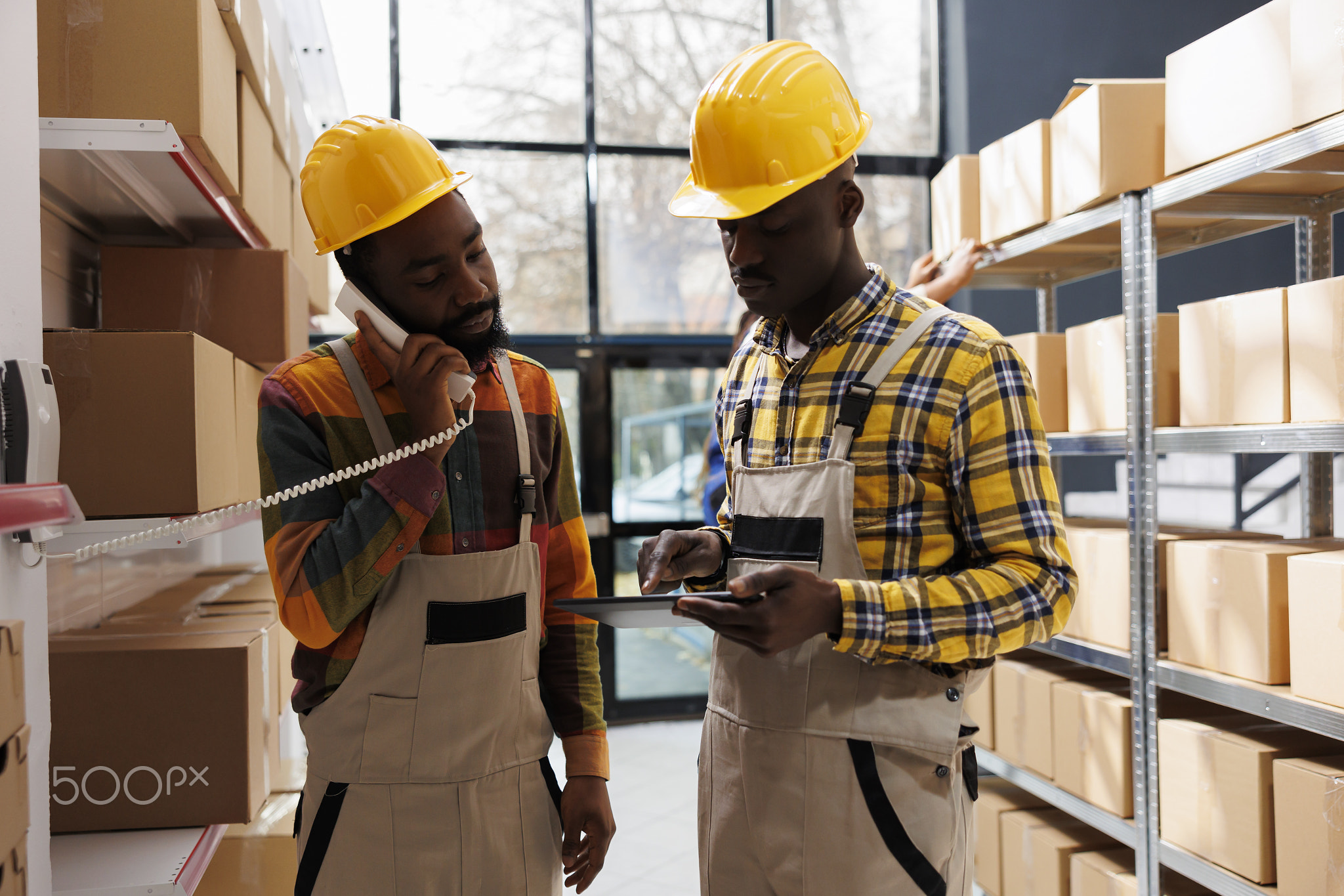 Storehouse managers checking order information on landline phone