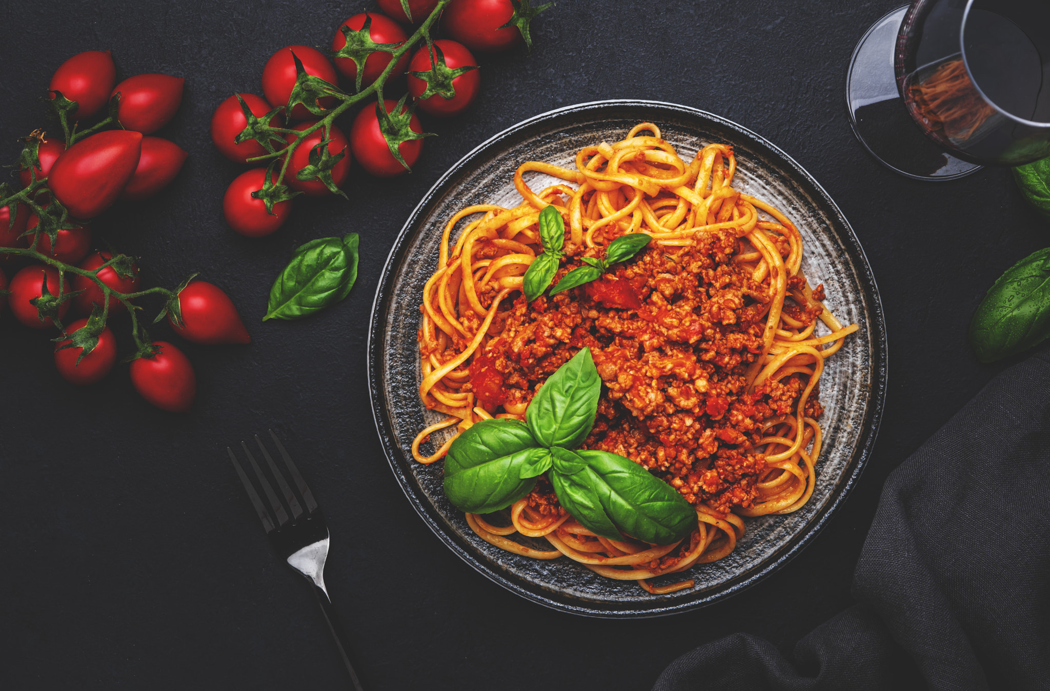 Spaghetti bolognese or pasta with minced meat in tomato sauce with green basil and chianti red wine