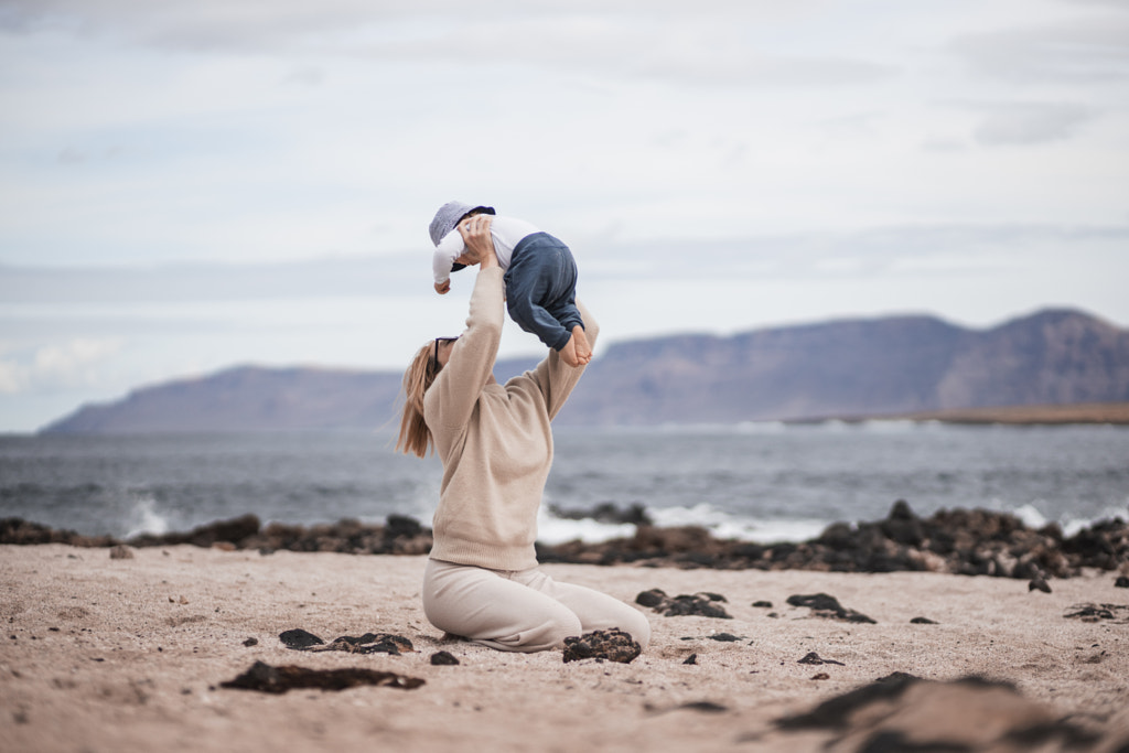 Mother enjoying winter vacations holding, playing and lifting his infant baby boy son high in the by Matej Kastelic on 500px.com