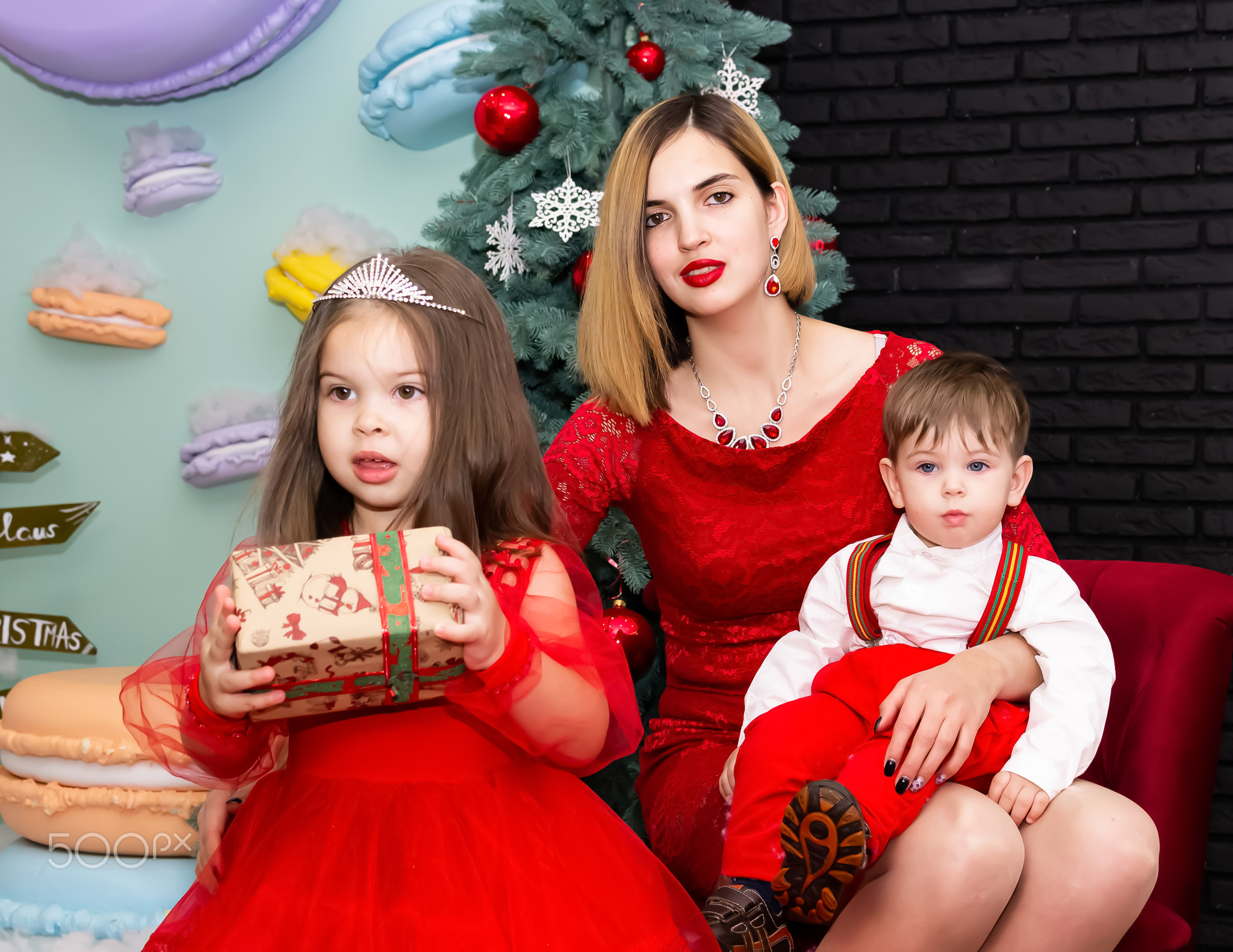 Family photo portrait. Mom and her two children in red clothes celebrate the Chistmas, new year