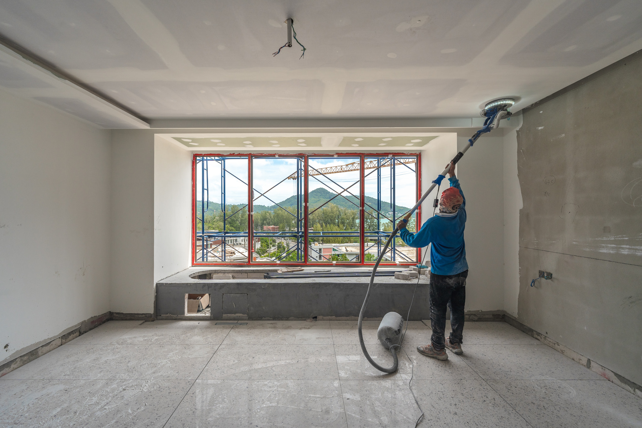 Laborer performing and polishing sand and cement screed wall on the construction site