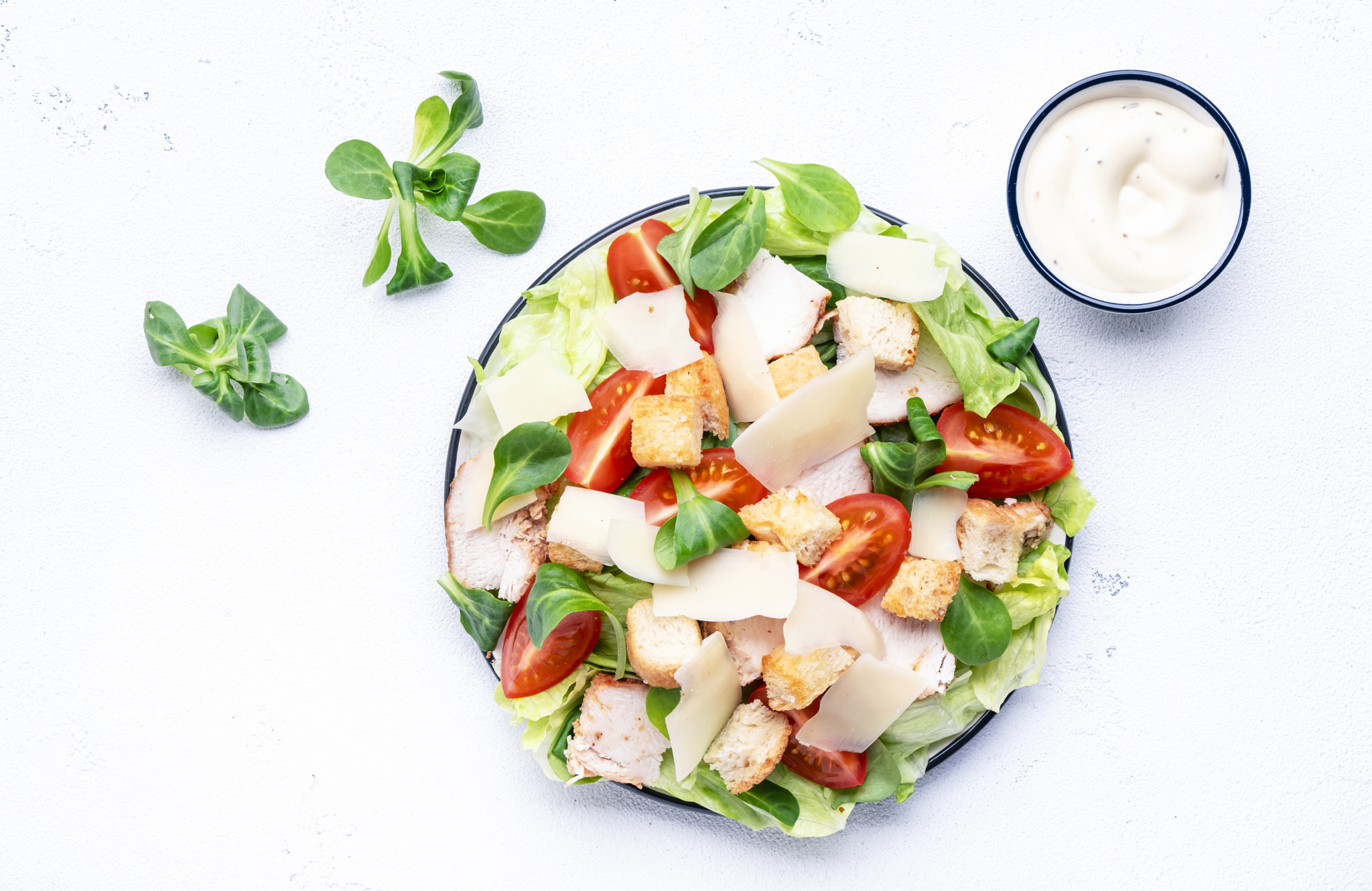 Caesar salad with chicken, iceberg salad, croutons, parmesan cheese and tomatoes with caesar dressin