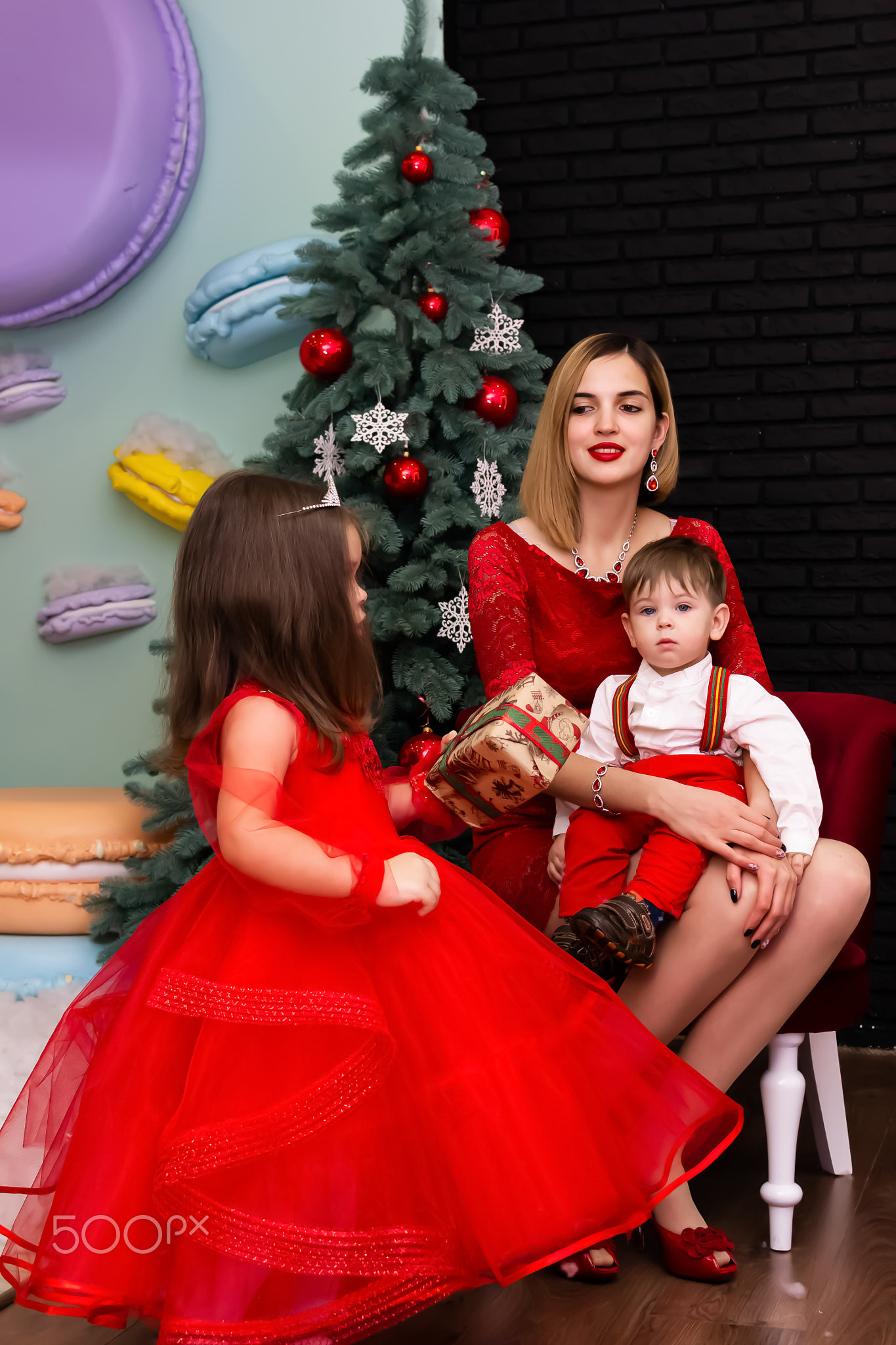 Family photo portrait. Mom and her two children in red clothes celebrate the Chistmas, new year