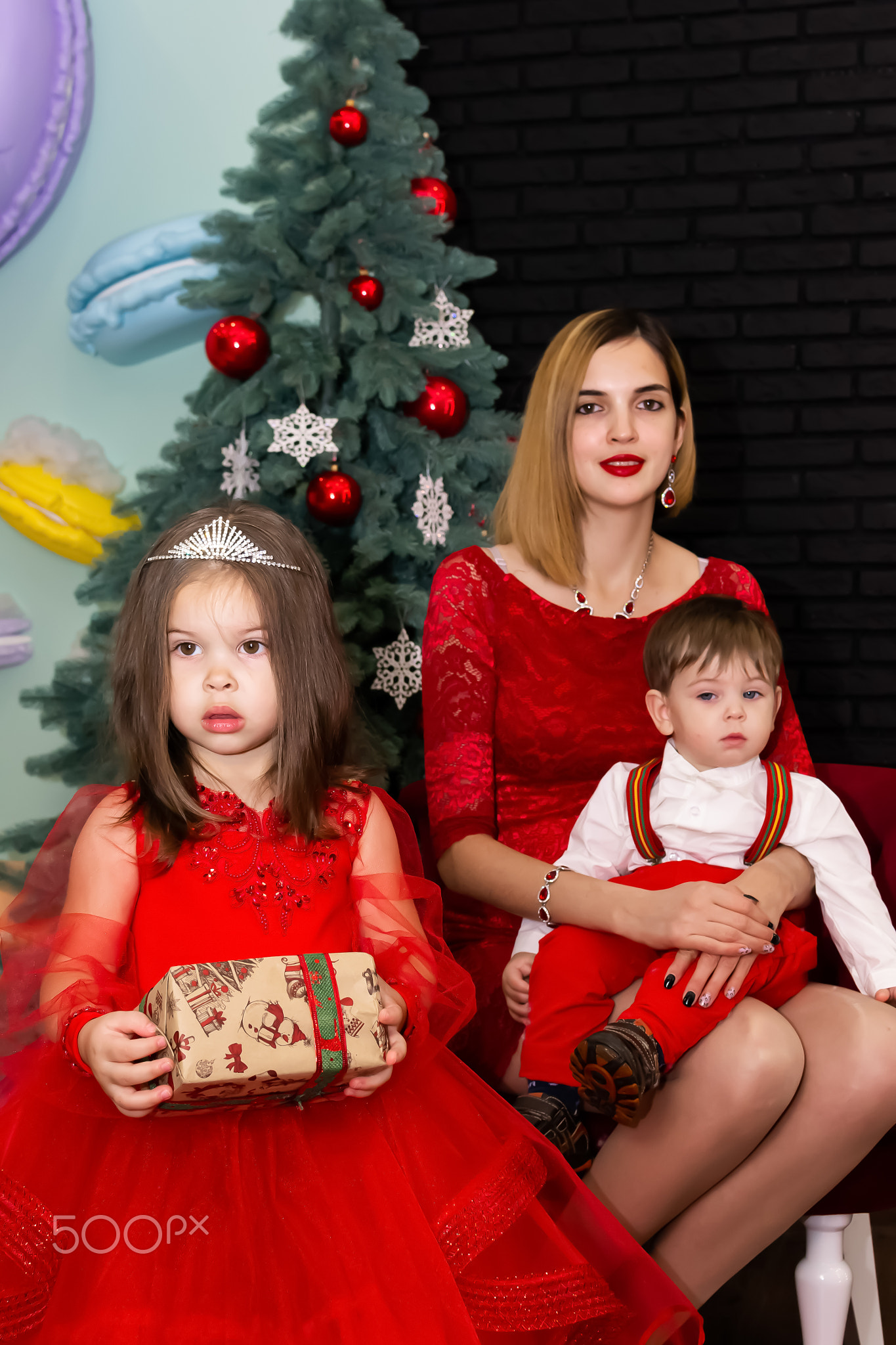 Family photo portrait. Mom and her two children in red clothes celebrate the Chistmas, new year