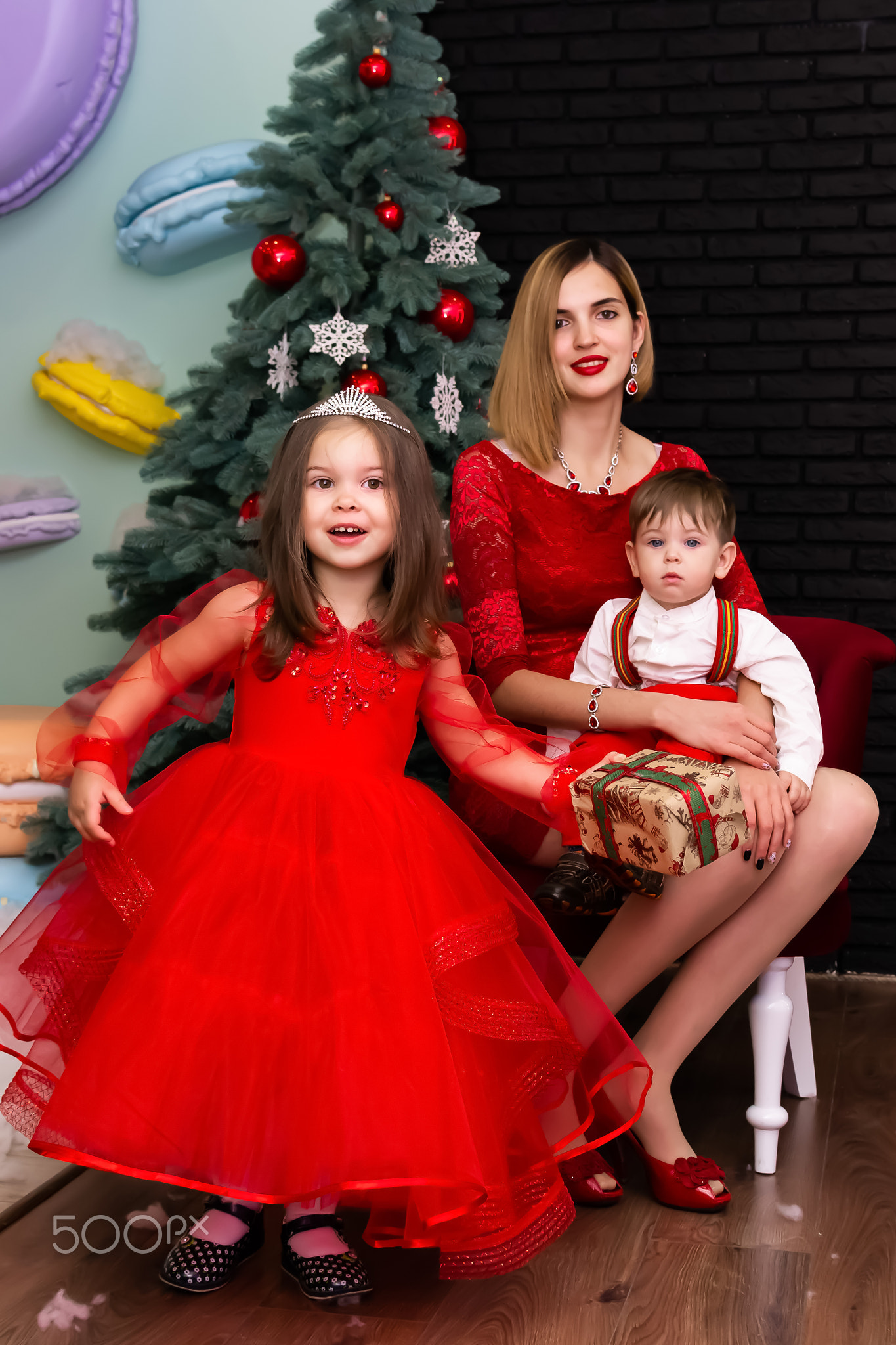 Family photo portrait. Mom and her two children in red clothes celebrate the Chistmas, new year