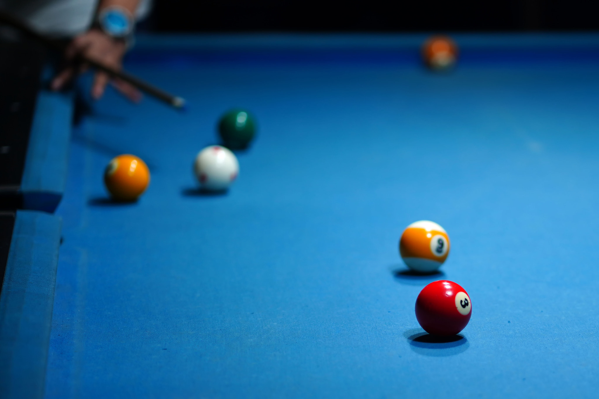 The hand holding the billiard cue, ready to make a precise strike on the billiard ball on the billia