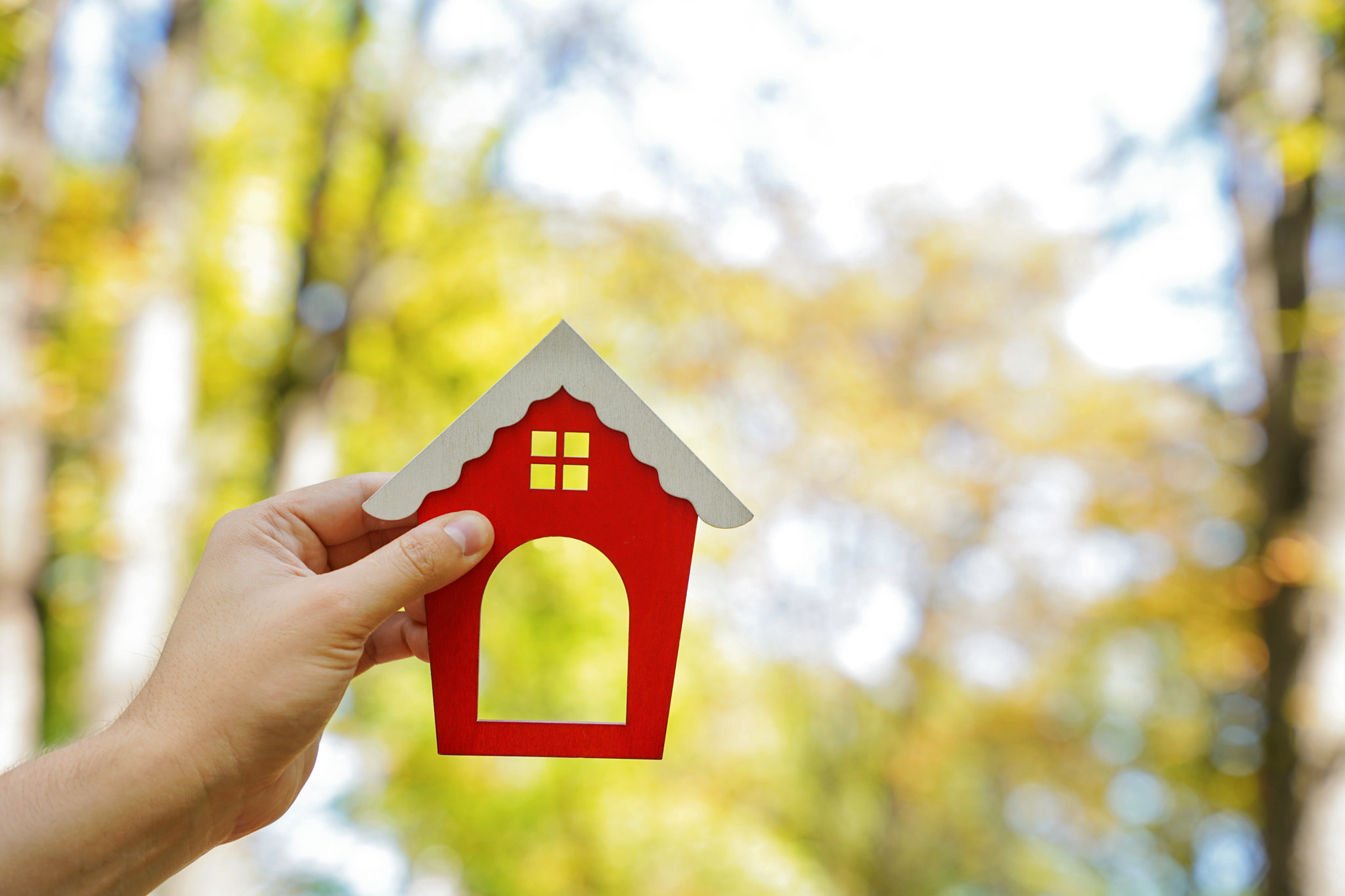 Miniature wooden house in the hands of a man outdoors. Real estate concept. Eco-friendly home. Buyin