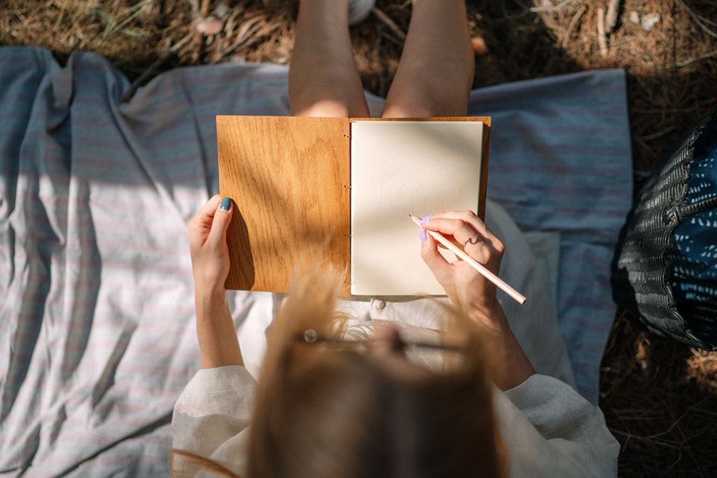 Low section of woman holding book while lying on bed at home by Olha Dobosh on 500px.com