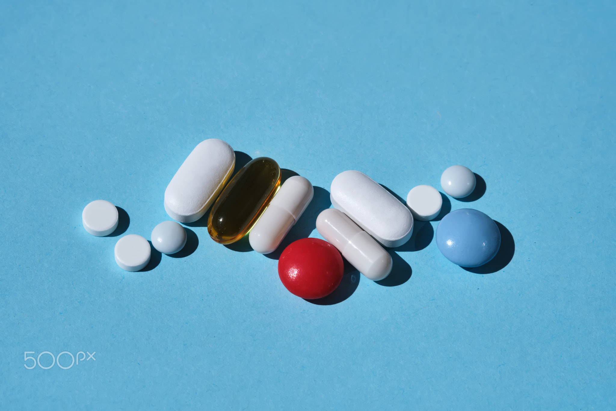 Various pills, supplements and vitamins on a blue.