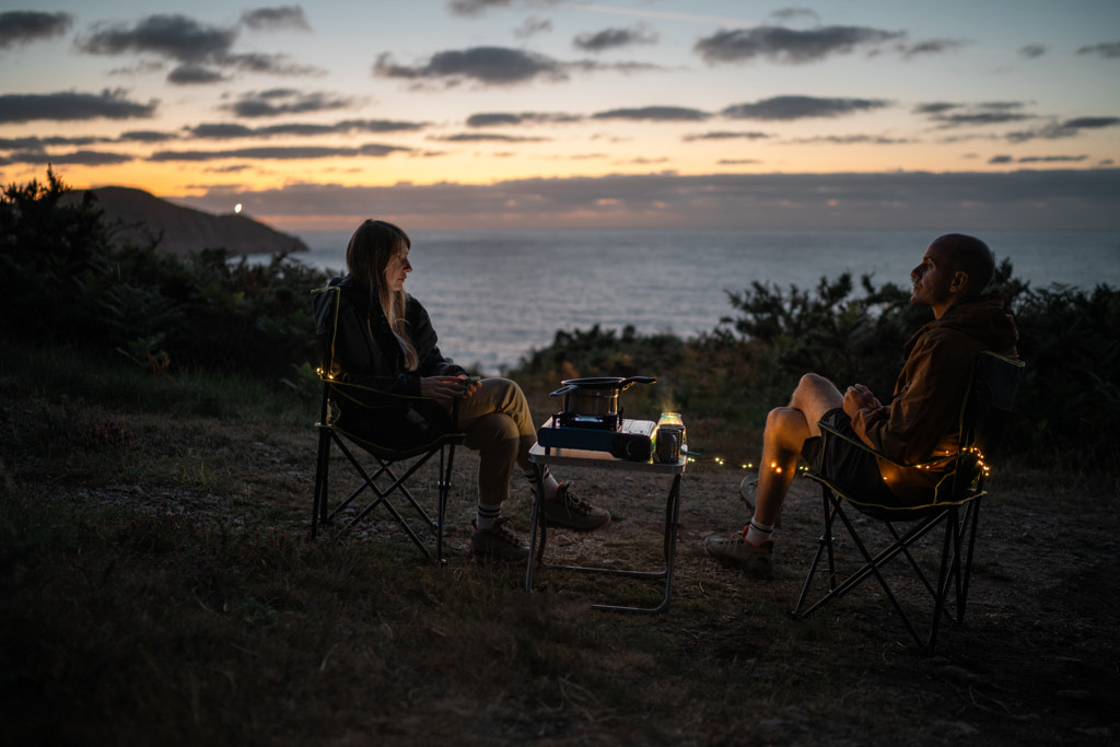 Couple sitting on chairs at beach against sky during sunset by Olha Dobosh on 500px.com