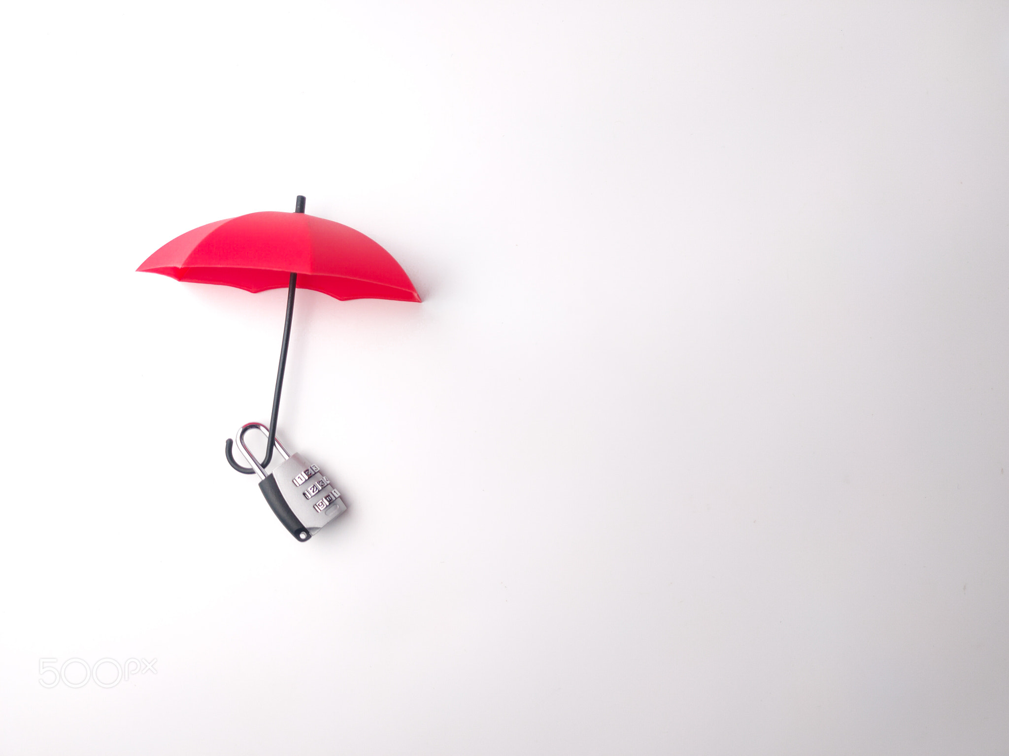 Silver padlock and red umbrella on a white background with copy space., Silver padlock and red umbre