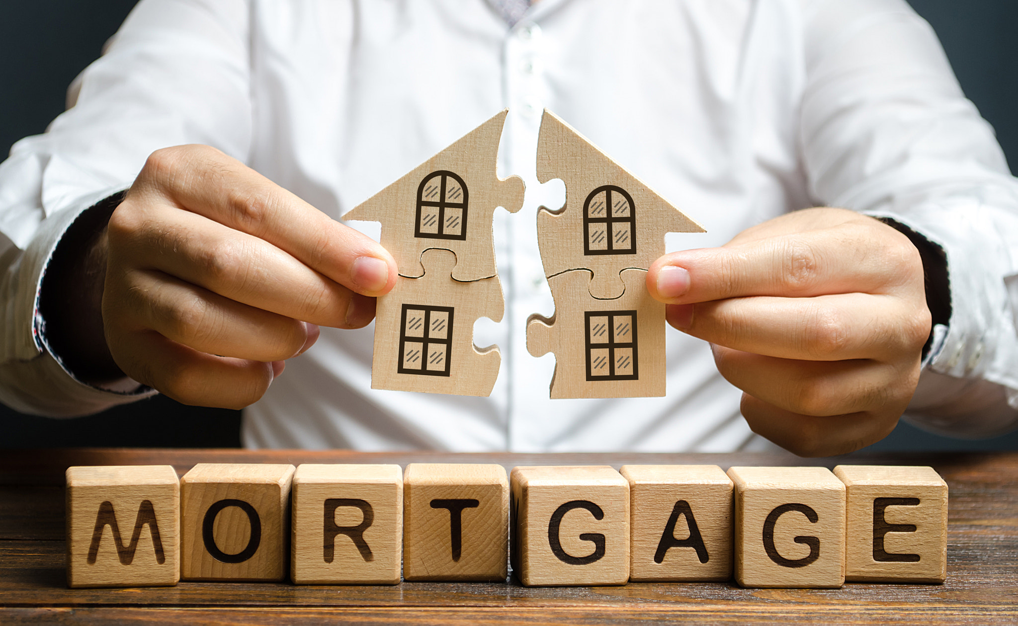 A man connects two puzzles into a whole house above the inscription Mortgage. Construction of your o