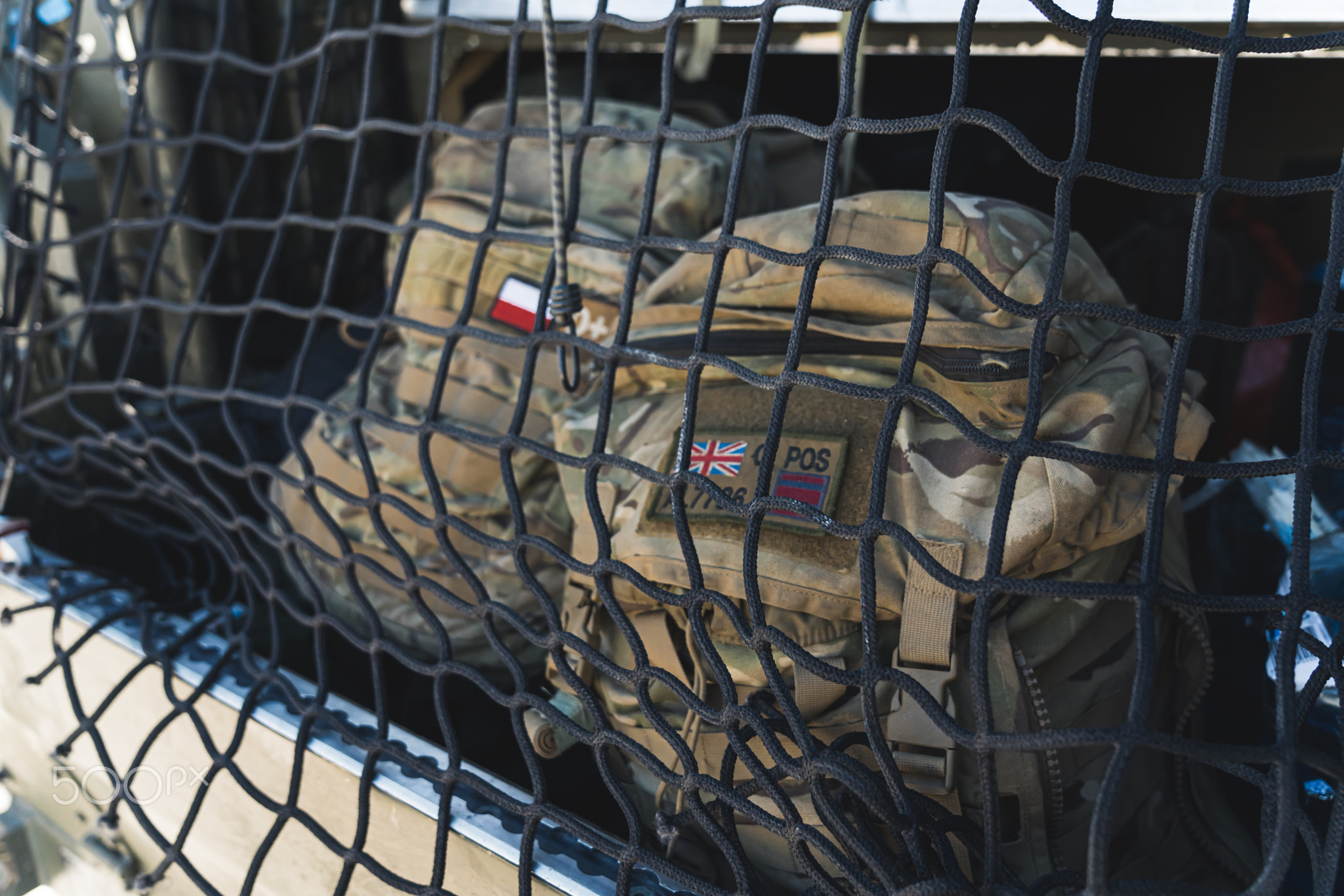 Two military backpacks behind a net packed onto a military transport