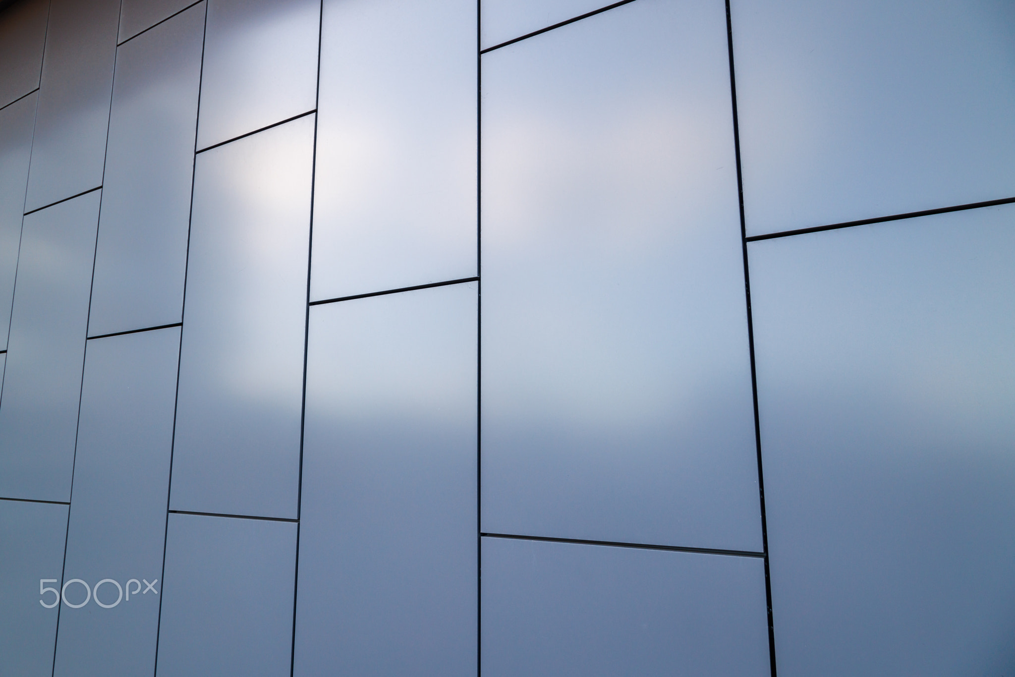 Outside wall of building covered with grayish blue painted metal rectangular panels - full-frame