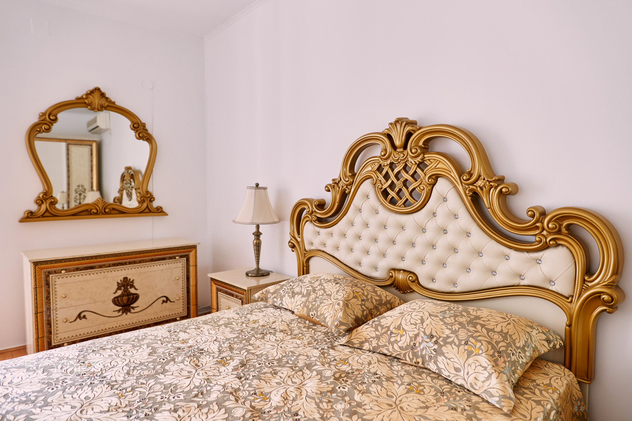 Double bed with a soft carved wooden headboard next to a mirror and