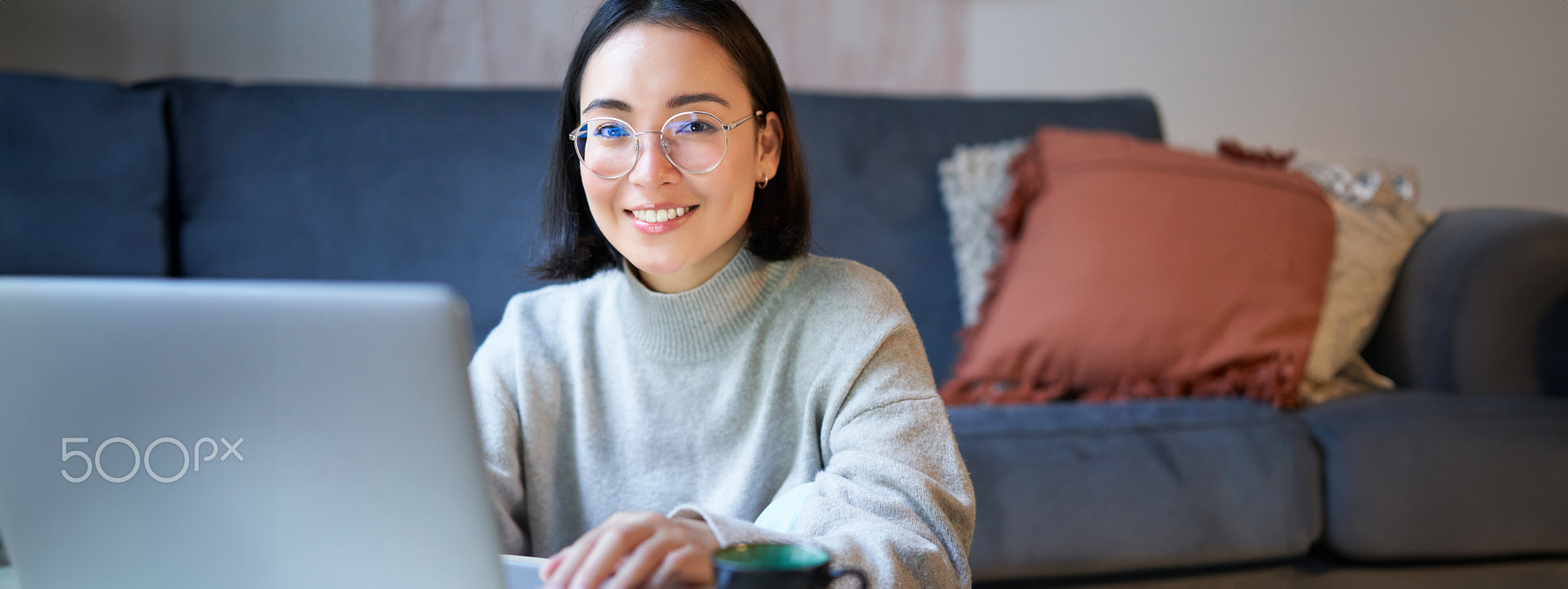 Self-employed young smiling woman, freelancer staying at home, working on remote from laptop