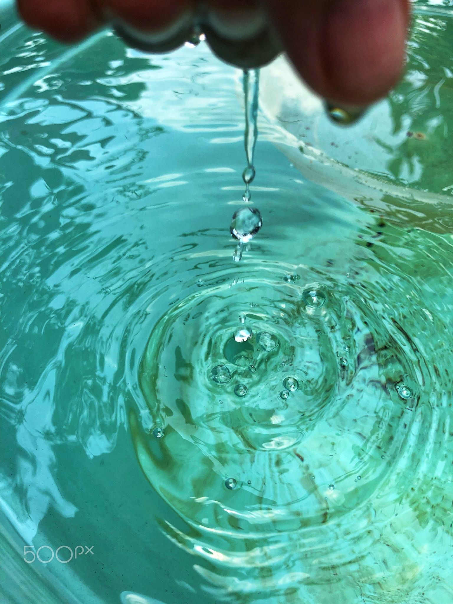 Water drops from hand on a big bucket during the day