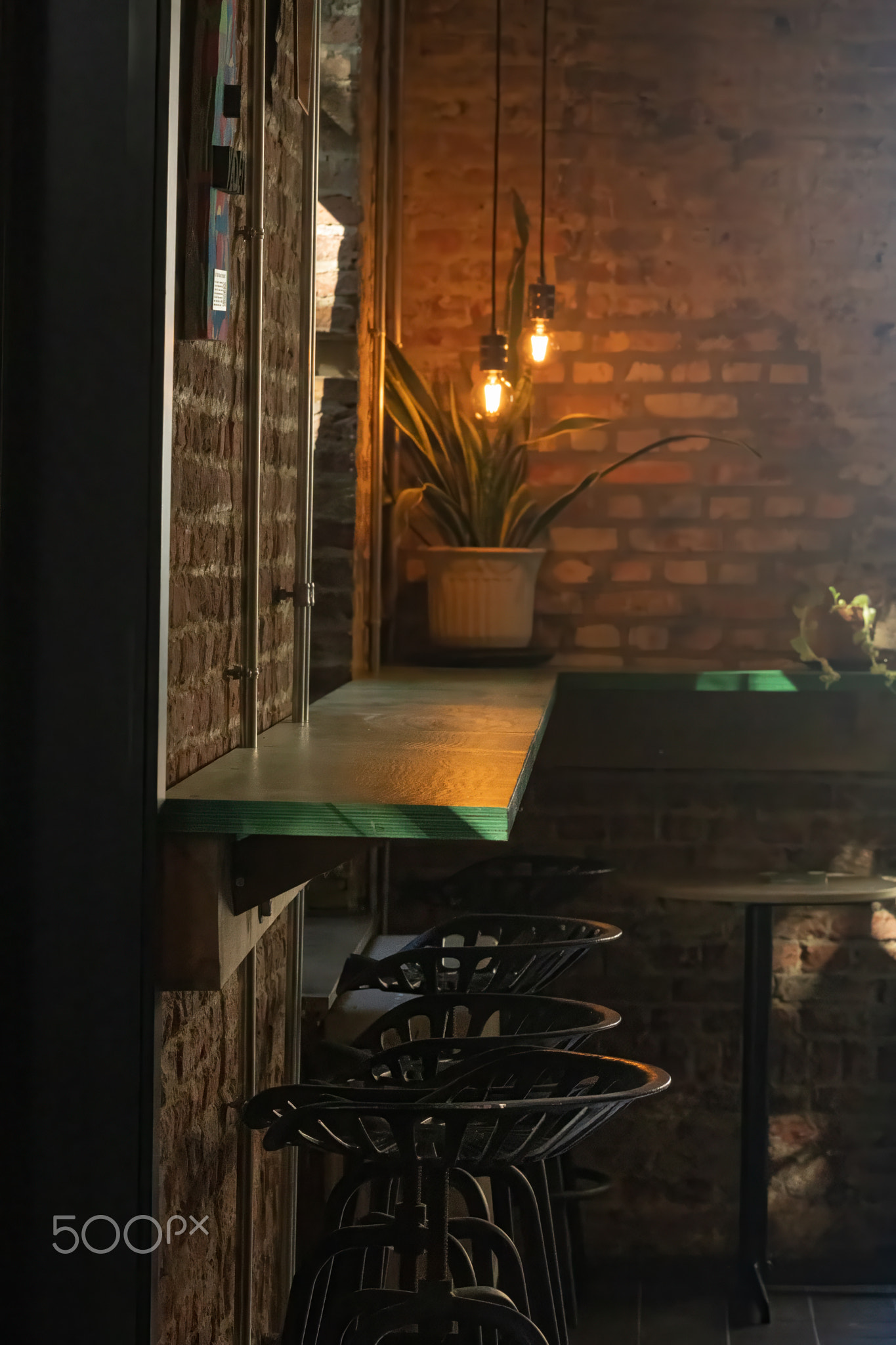 Contemporary bar setting with a row of chairs and a brick wall in the background