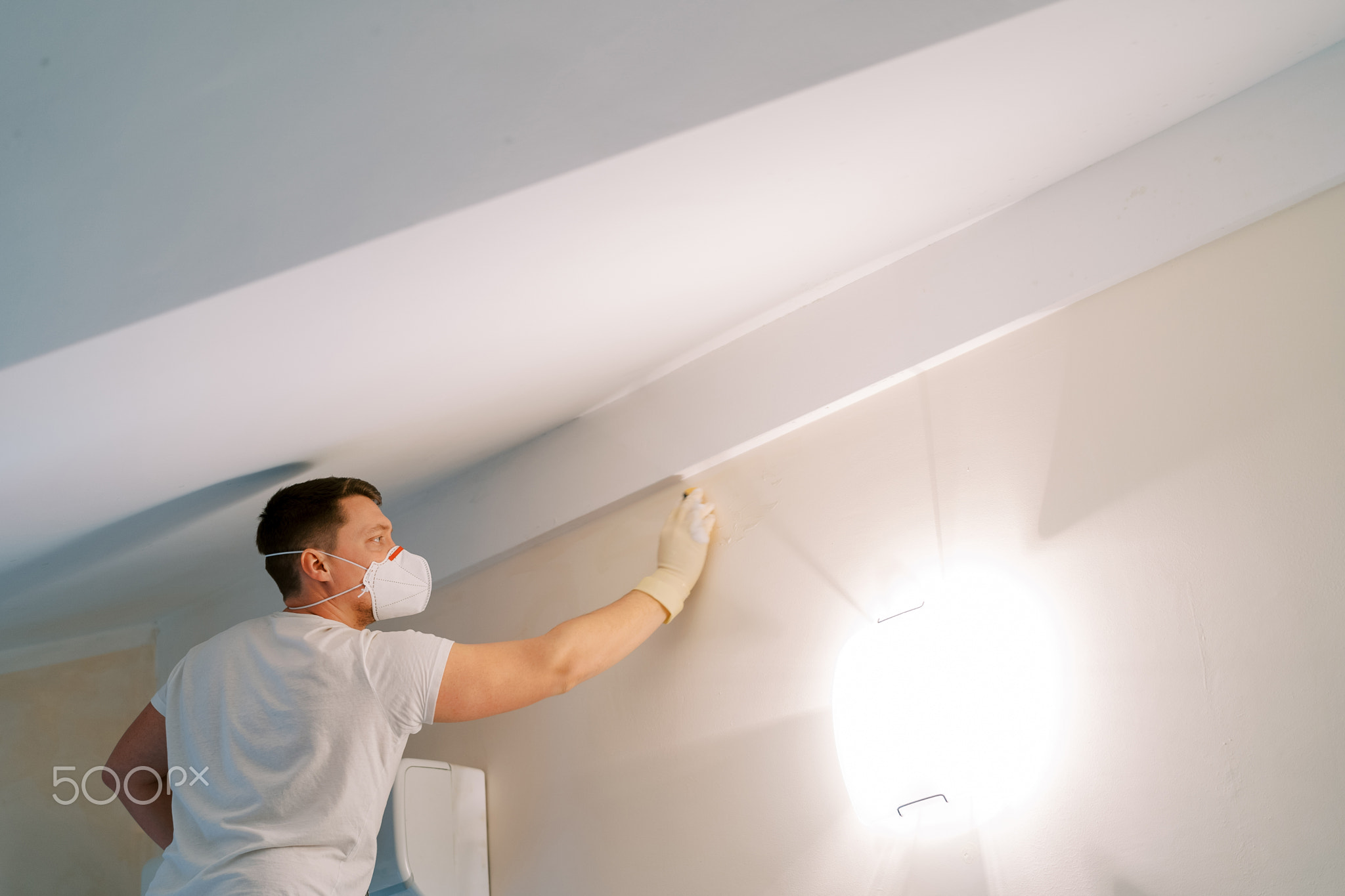 Man in a mask and gloves washes a fungus wall with a sponge