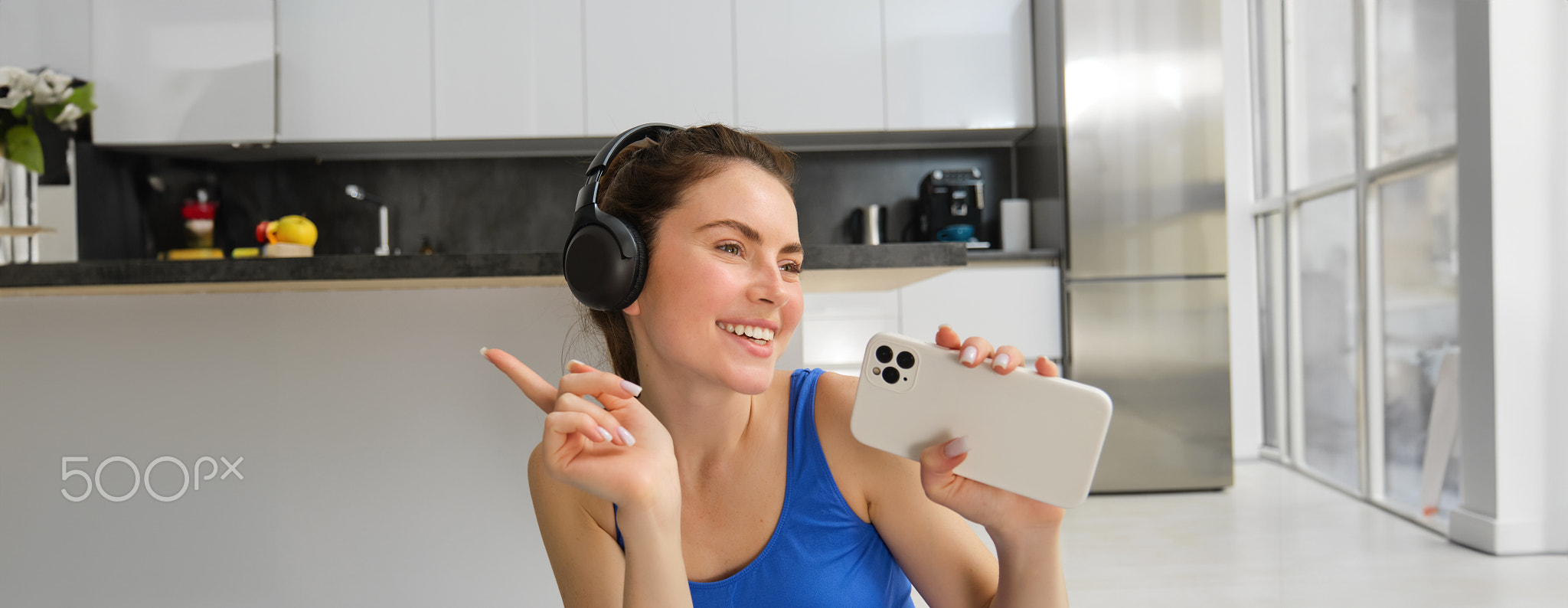 Close up portrait of young happy woman, workout at home, listens music in wireless headphones