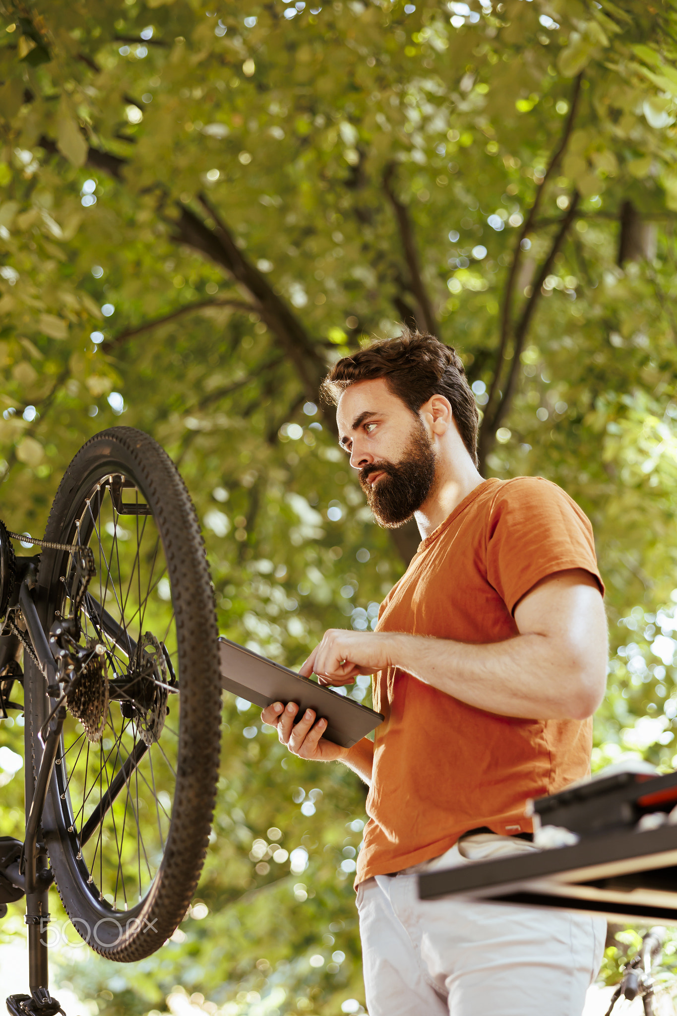 Man fixing bicycle wheel with tablet