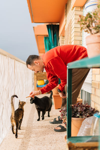 Young man feeding his cat to his puppy by Olha Dobosh on 500px.com