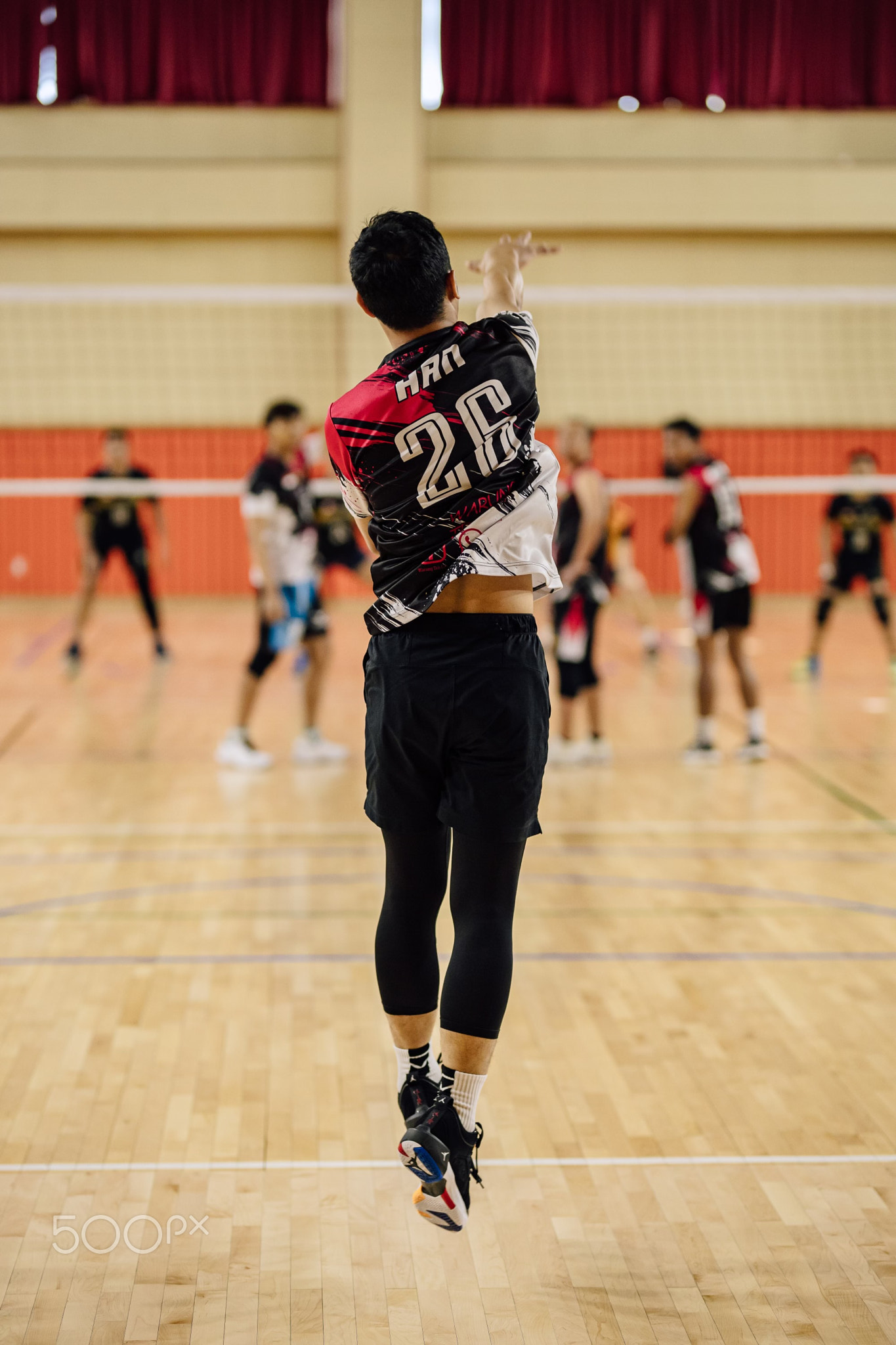 Behind the back of a man jumping while playing volleyball