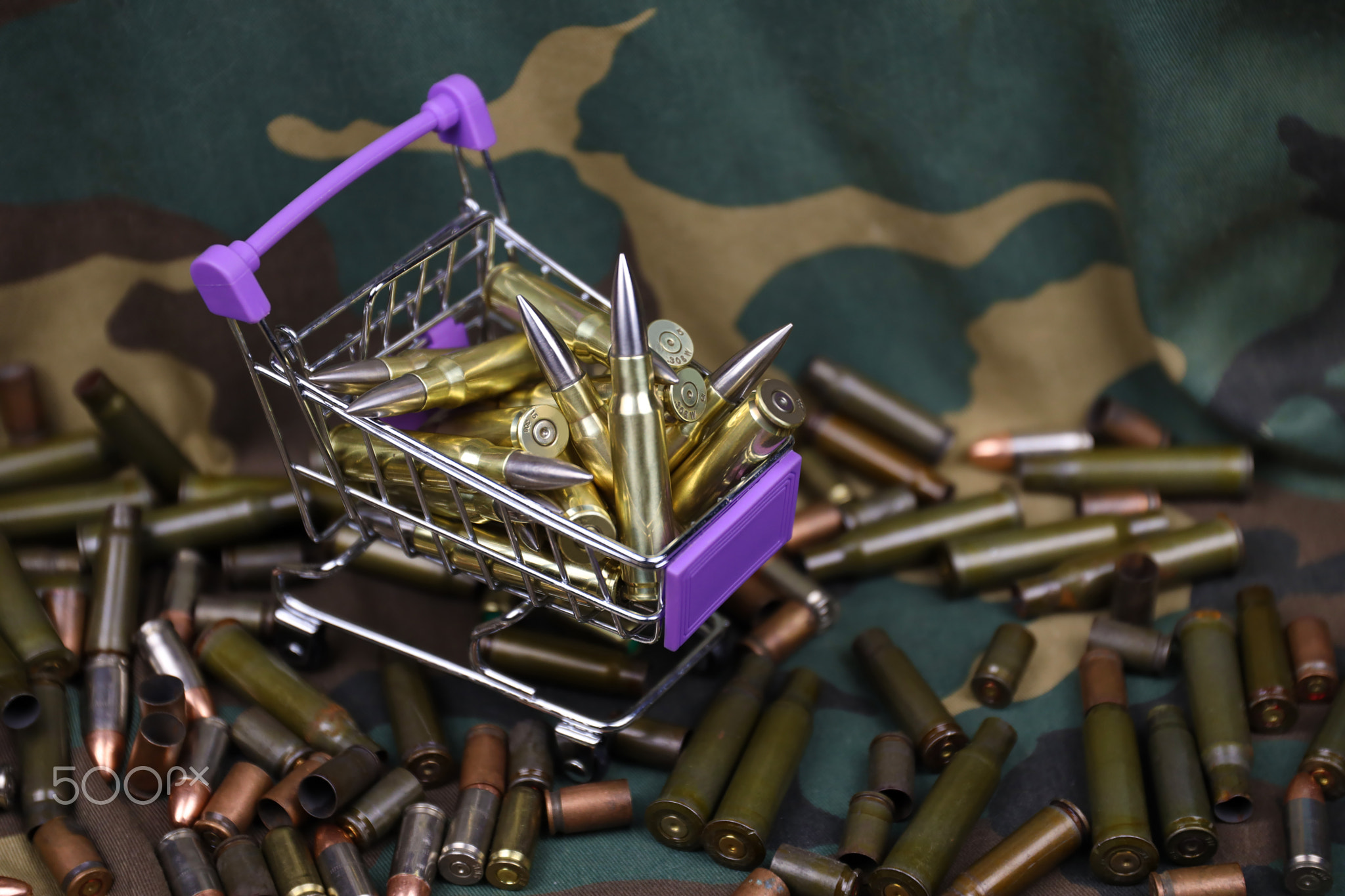 Rifle cartridges in small shopping cart. Big caliber ammo cartridges with a small shopping basket