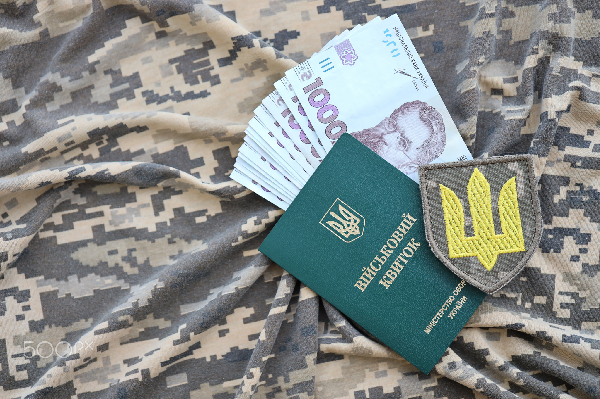 Symbol of Ukrainian army and military ID with bunch of money on the camouflage uniform of a