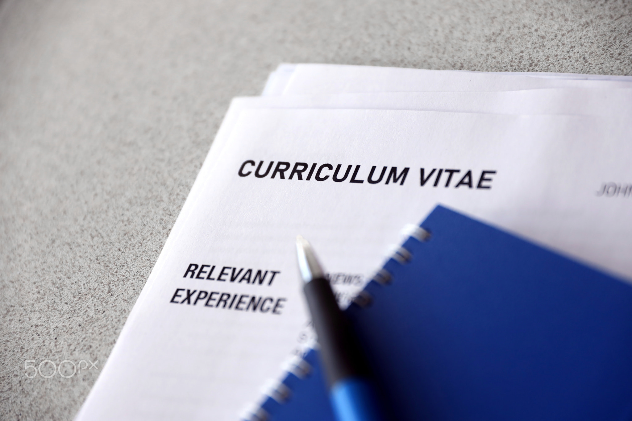 Top view of stack of office documents including resume and cv forms on the desk close to pen and