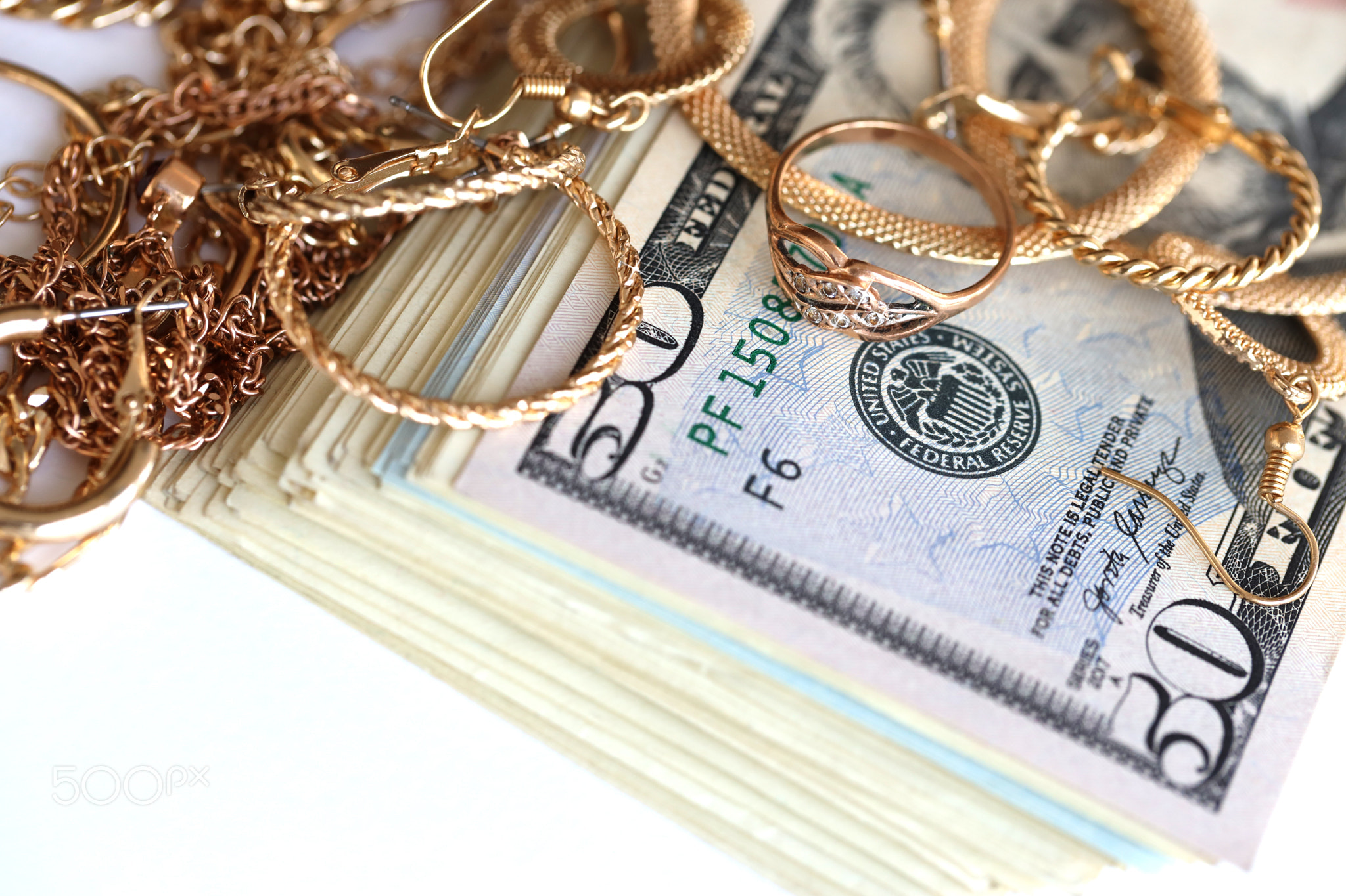 Many expensive golden jewerly rings, earrings and necklaces with big amount of US dollar bills on