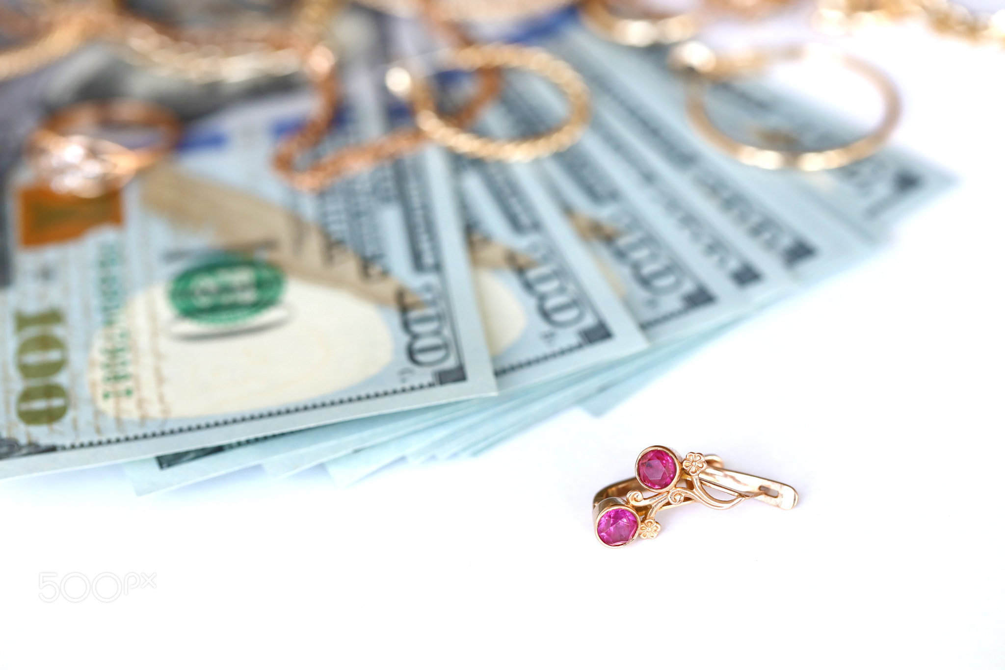 Many expensive golden jewerly rings, earrings and necklaces with big amount of US dollar bills on