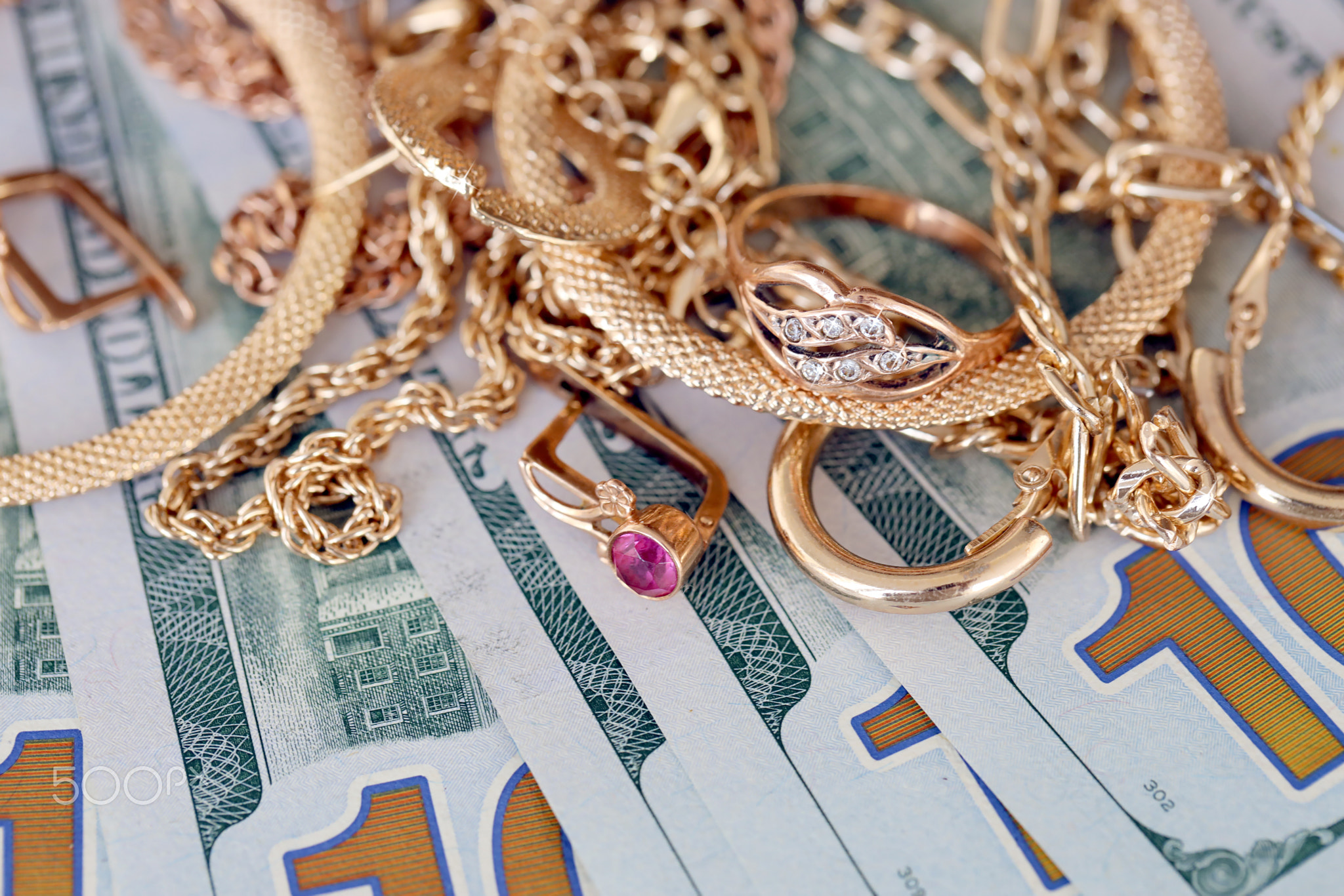 Many expensive golden jewerly rings, earrings and necklaces with big amount of US dollar bills on