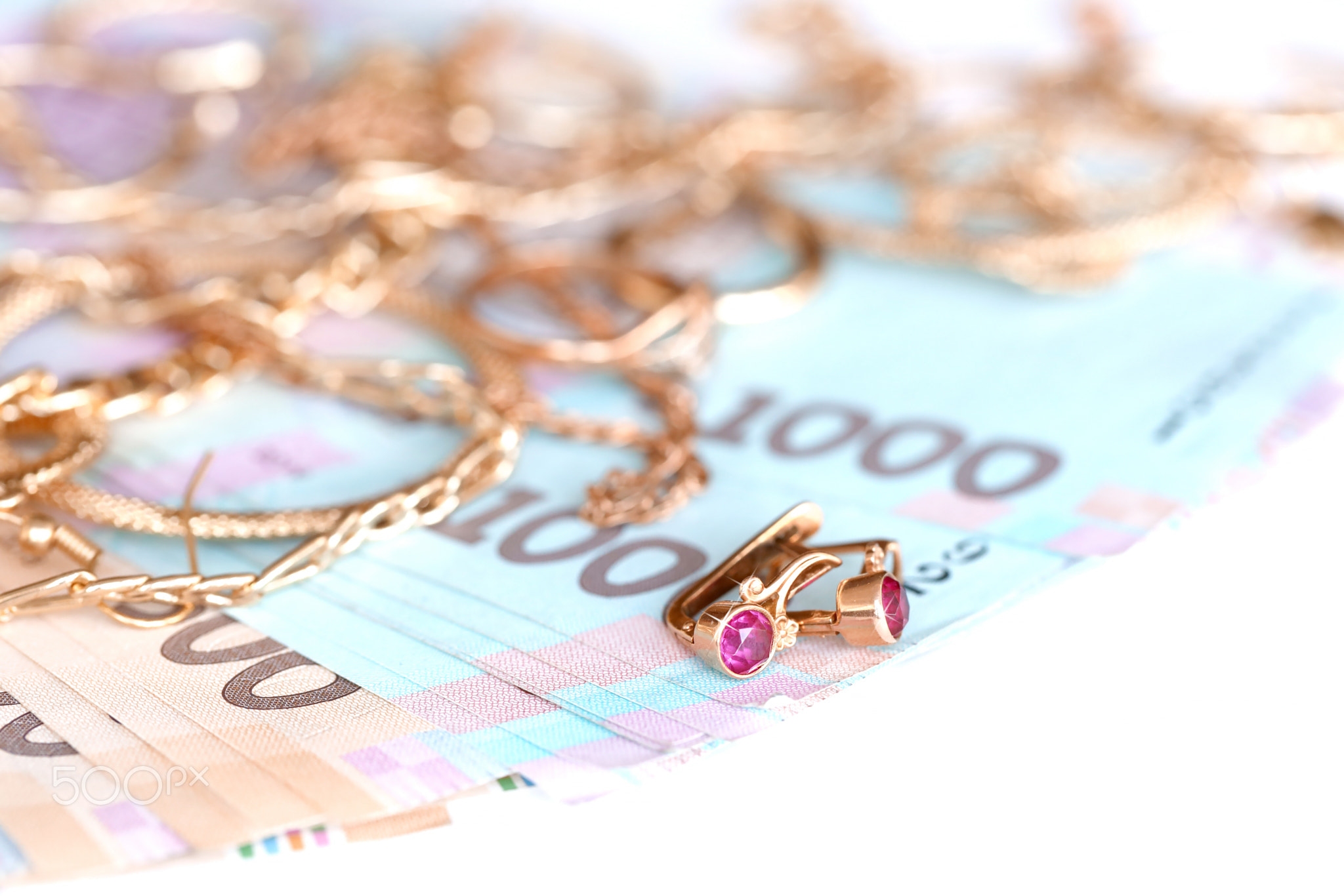 Many expensive golden jewerly rings, earrings and necklaces with big amount of Ukrainian money bills