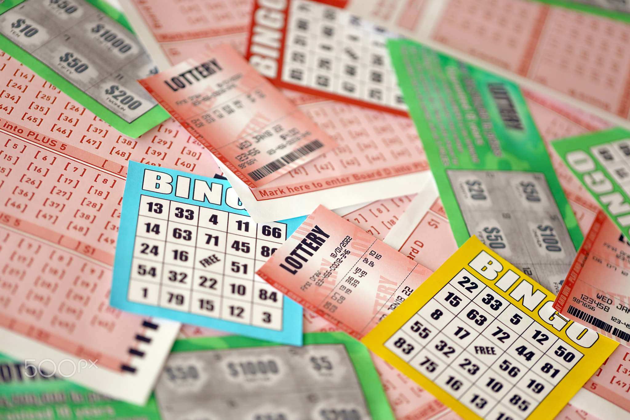 Many used lottery tickets, bills with numbers and bingo playing boards in big pile. Gambling and