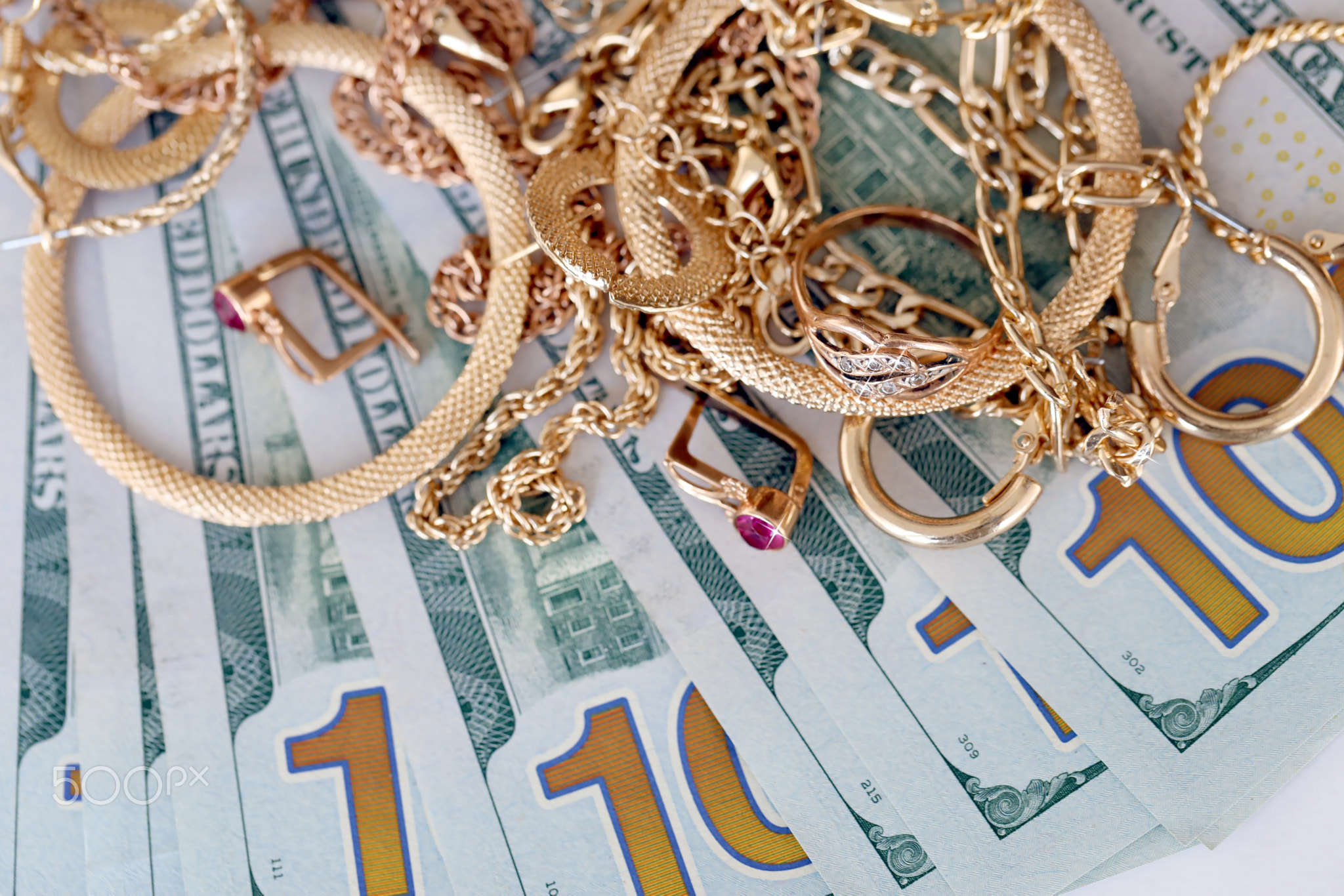 Many expensive golden jewerly rings, earrings and necklaces with big amount of US dollar bills on