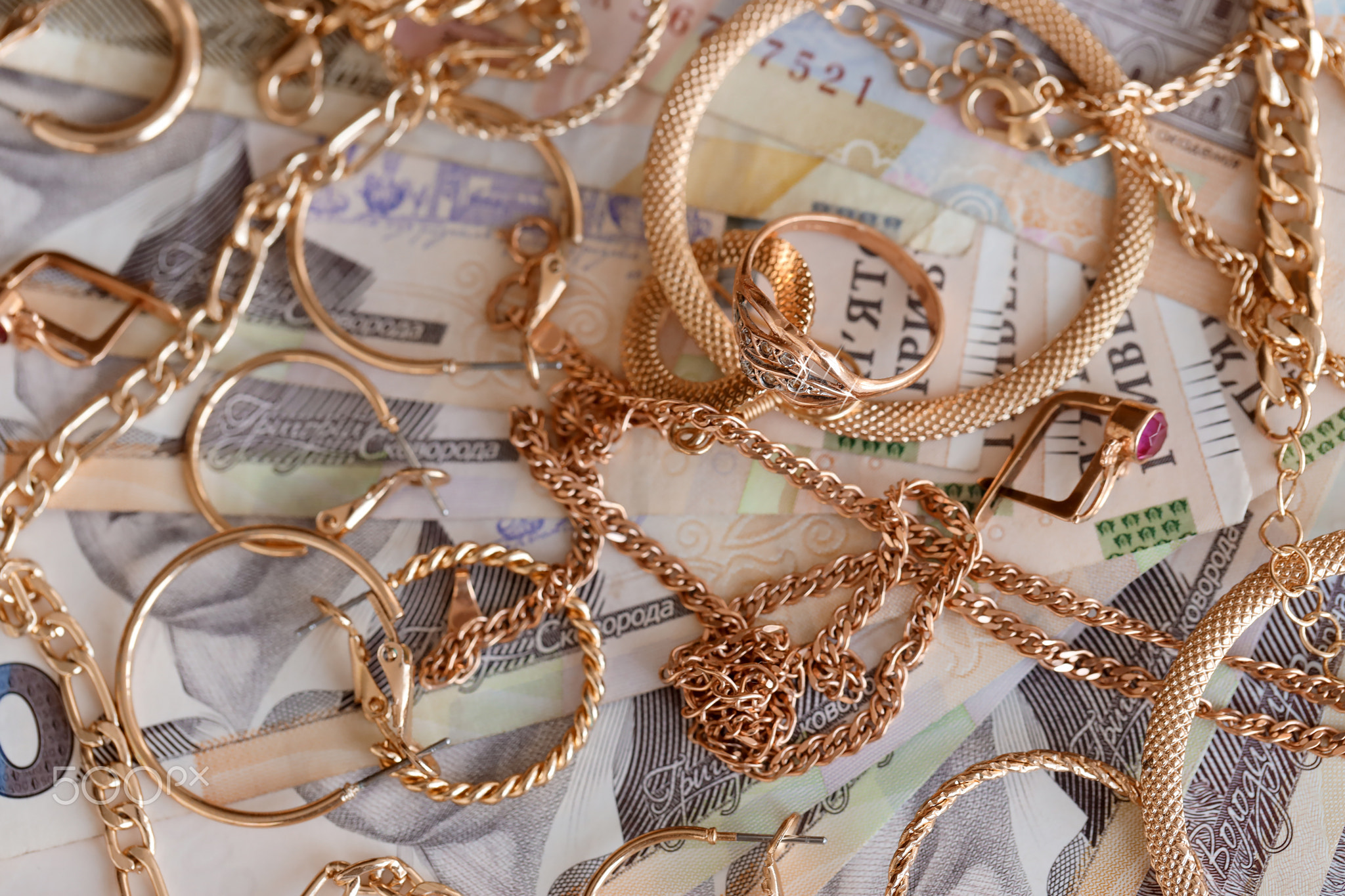 Many expensive golden jewerly rings, earrings and necklaces with big amount of Ukrainian money bills