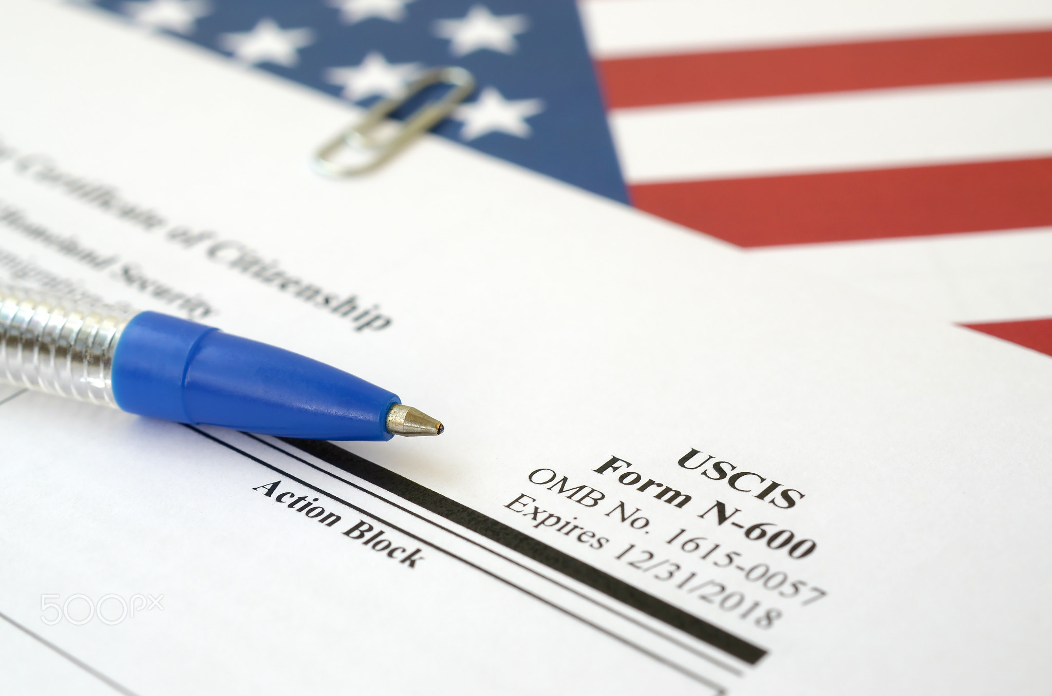 N-600 Application for Certificate of Citizenship blank form lies on United States flag with blue pen