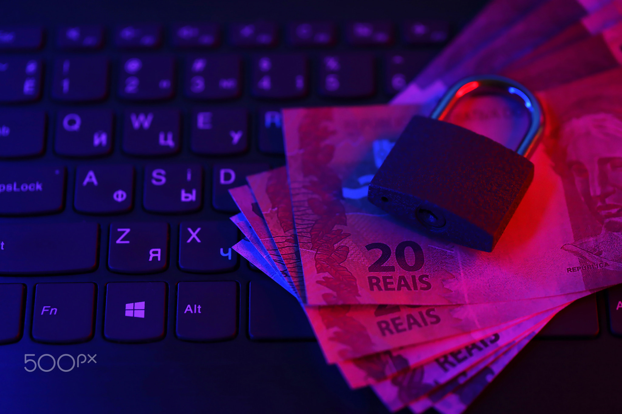 Closed padlock with brazilian reais money bills on laptop keyboard close up. Safe online banking or