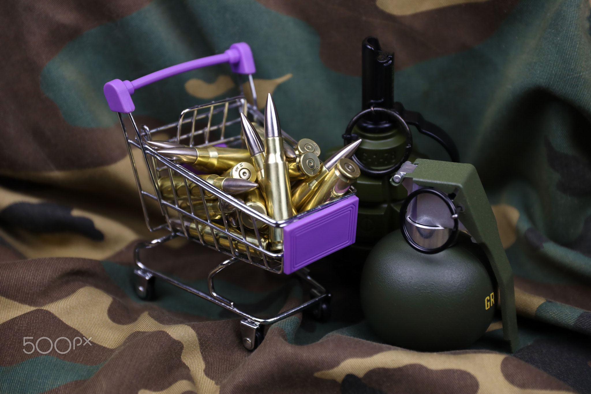 Rifle cartridges in small shopping cart. Big caliber ammo cartridges and hand grenades with a small